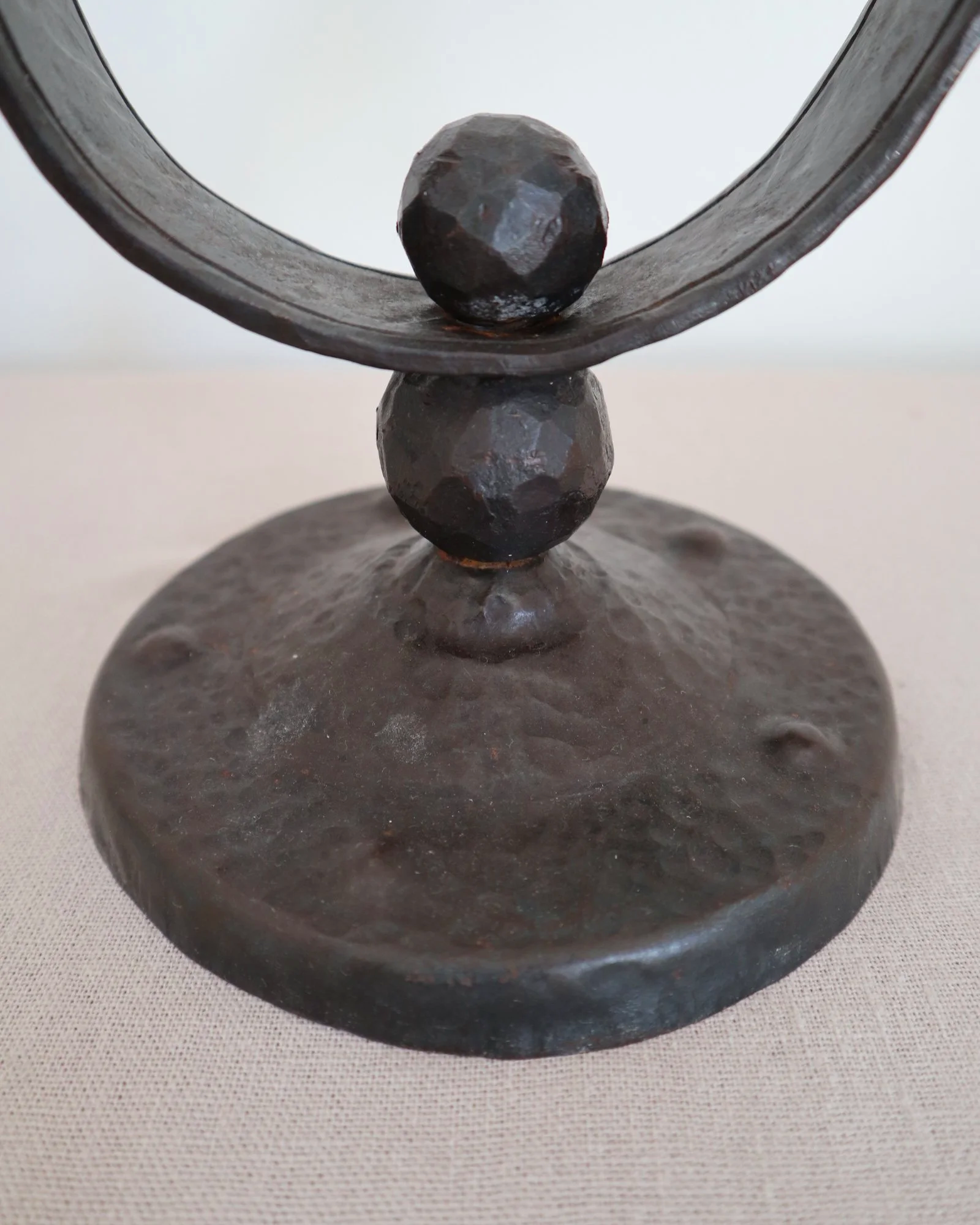 Heavy Brutalist style forged iron candleholder with off set double arms and circular base.