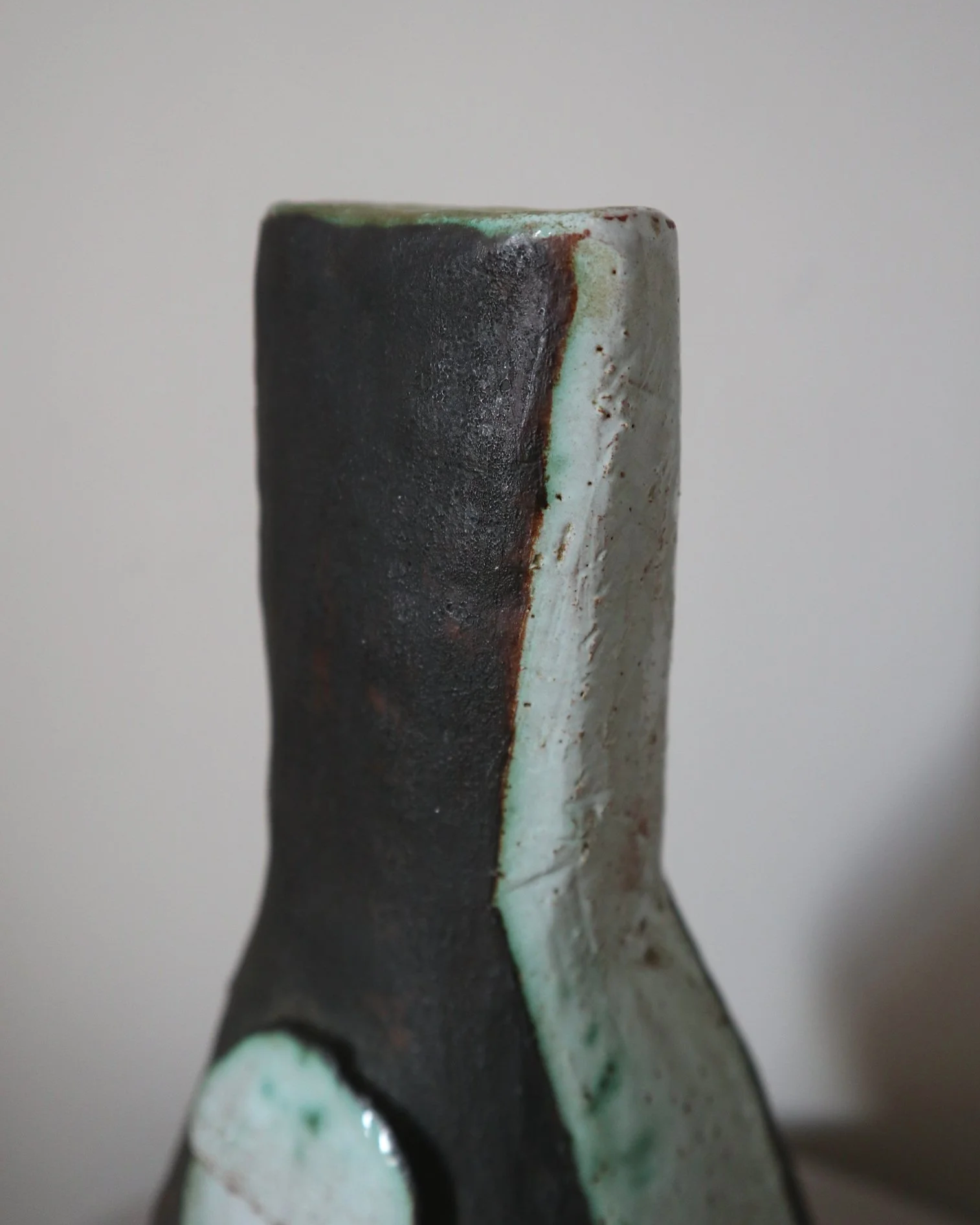 Vintage hand-built ceramic Brutalist art vase, featuring an abstract, asymmetrical design with textured white, dark brown, and subtle green glazes.