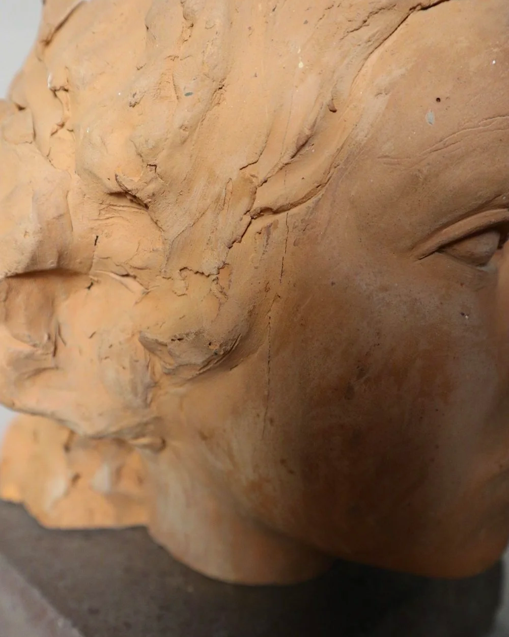 A signed, 20th century art studio terracotta female bust with stone display plinth.