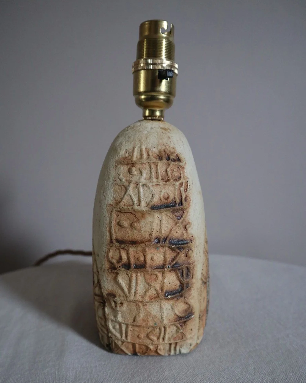 Small Brutalist stoneware table lamp by British potter Bernard Rooke. With stamped, rune-like impressions. Circa 1970s.