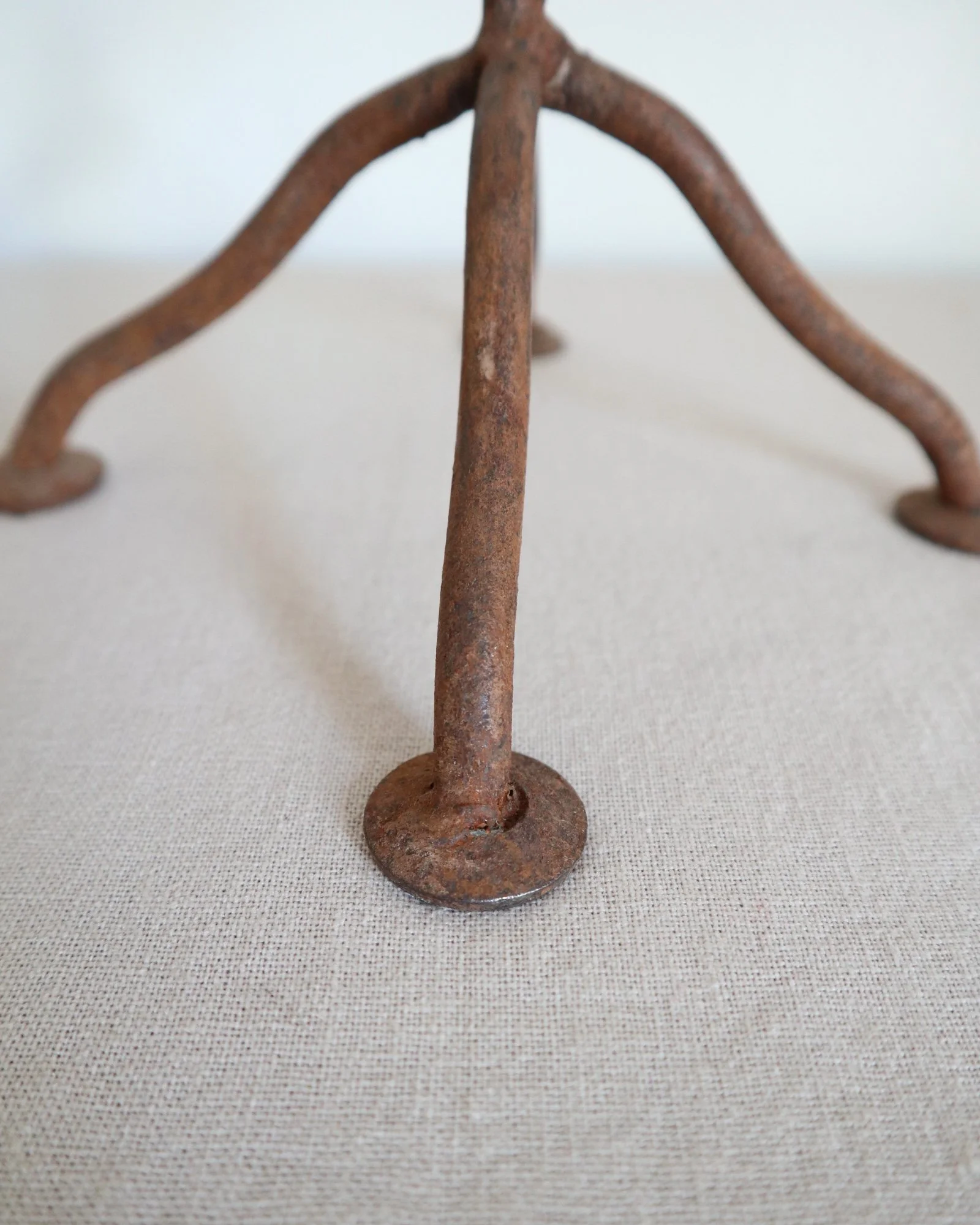 Pair of mid-century, sculptural hand crafted wrought iron 3-arm candle holders with decorative leaves and four footed base.