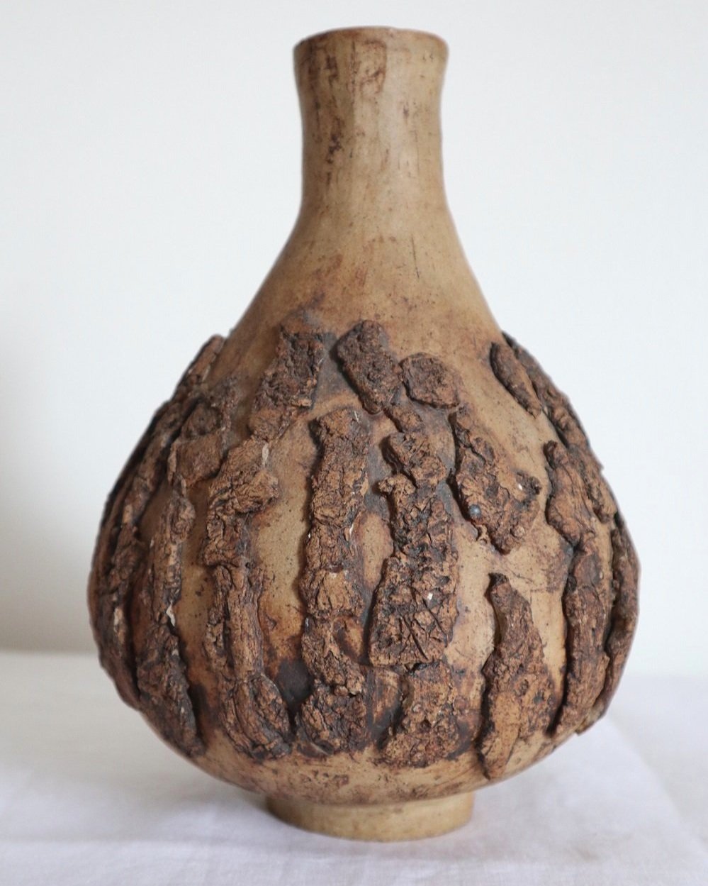 Studio pottery brown ceramic decorative vase with textured, tree bark effect decorations and a tapered neck. Age unknown.