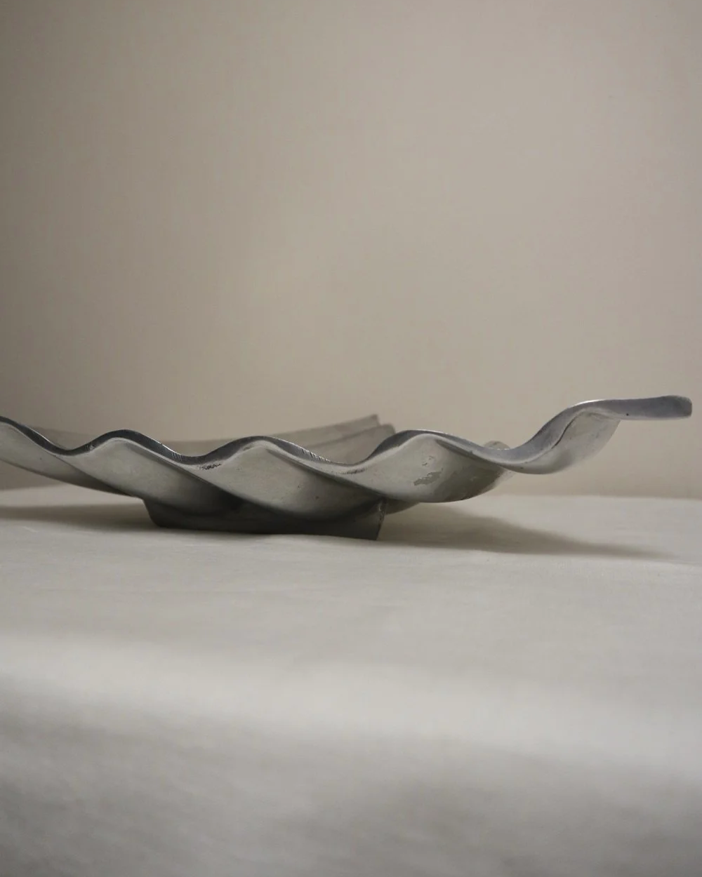 Large mid century, shiny cast aluminium triangular display dish with wavy edge.