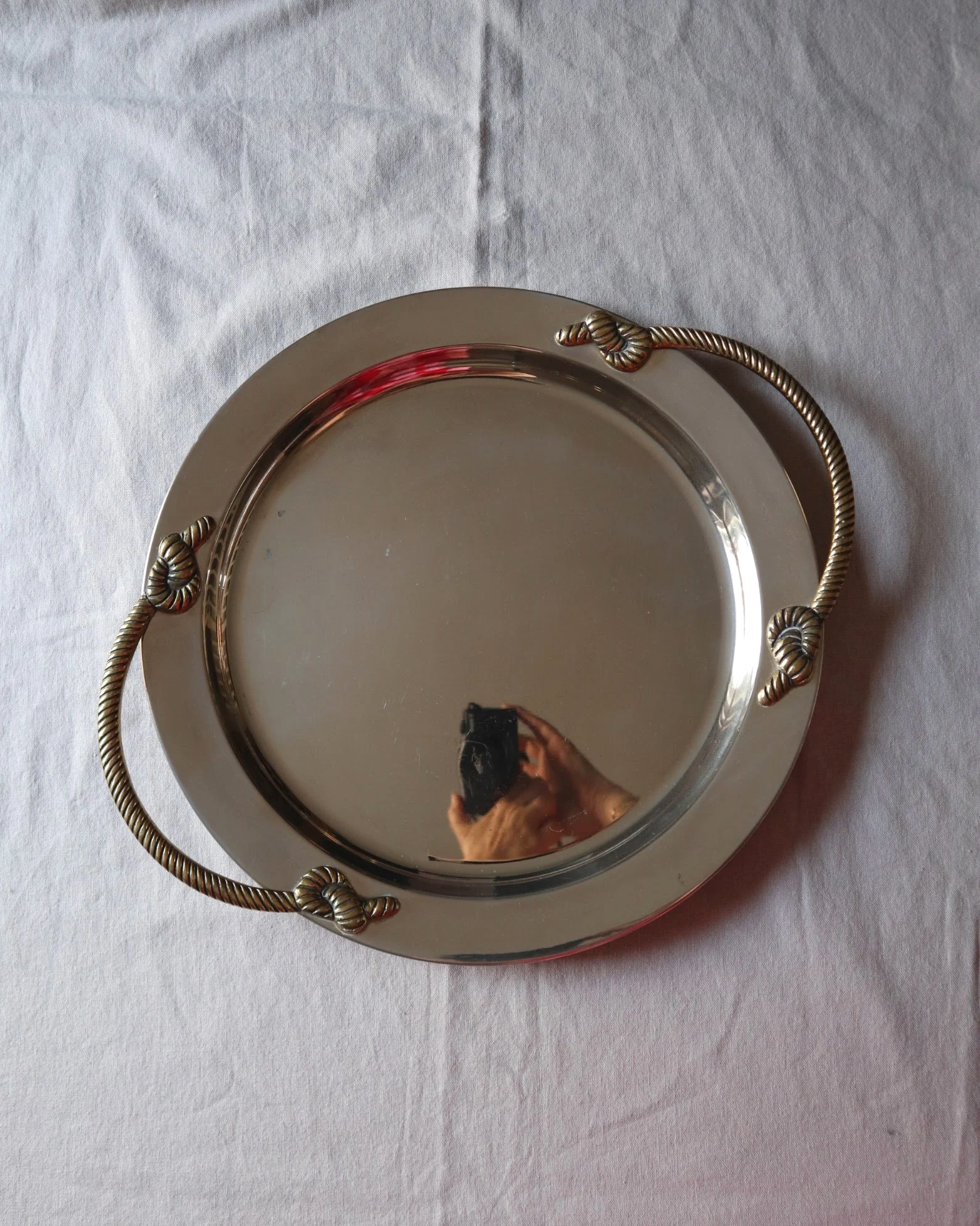 Large mid century circular shiny metal serving tray with elegant brass rope design handles.
