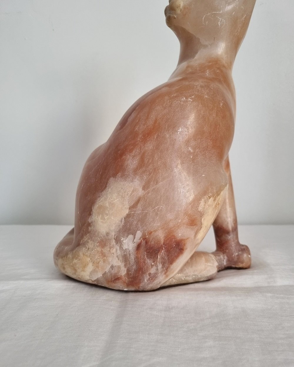 Vintage, heavy hand carved soft pink alabaster cat with striking natural grain and smooth lines.