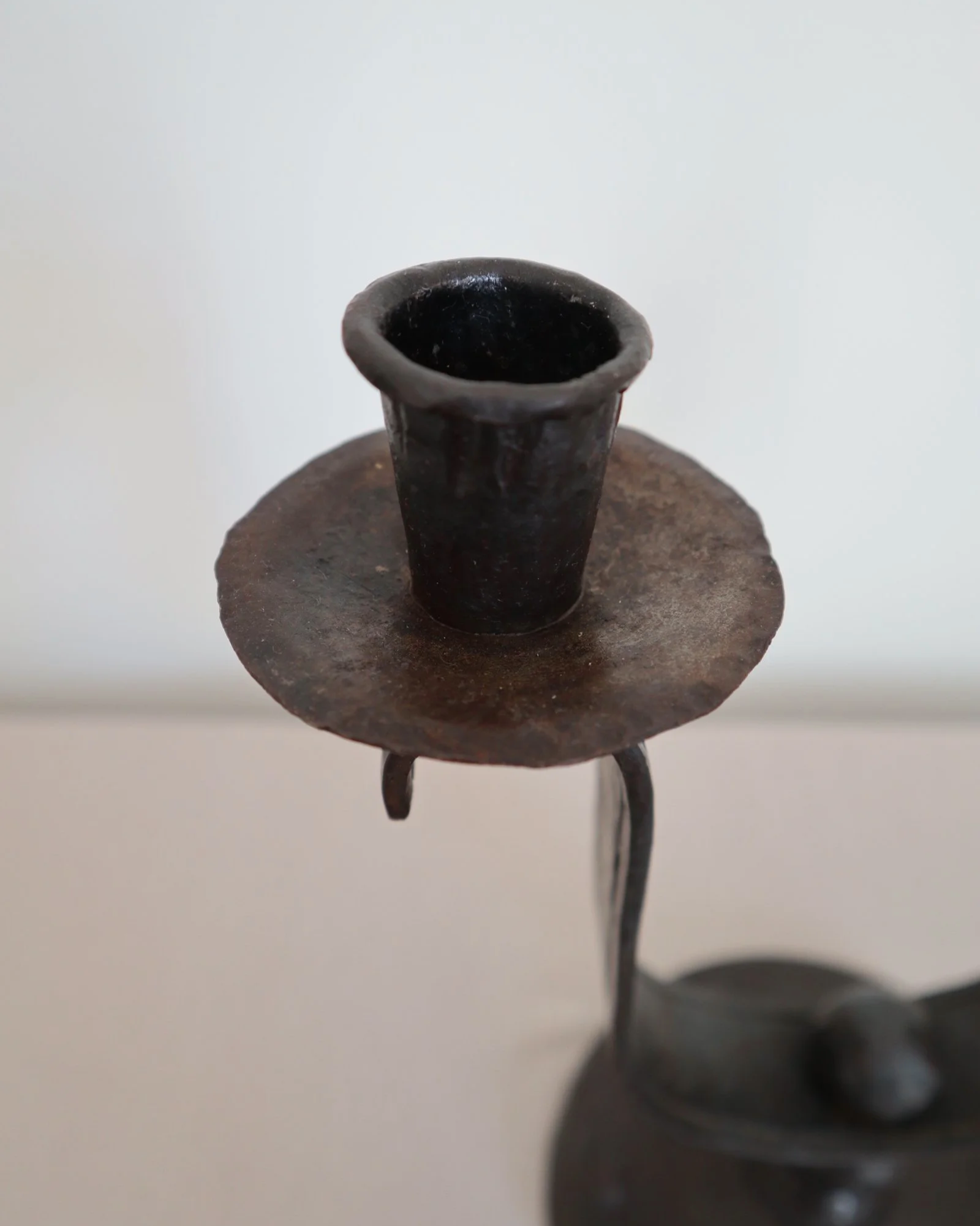 Heavy Brutalist style forged iron candleholder with off set double arms and circular base.