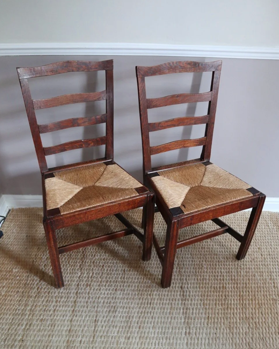 Pair of sculptural rustic oak ladder back dining chairs with rush seats, circa 1930s.