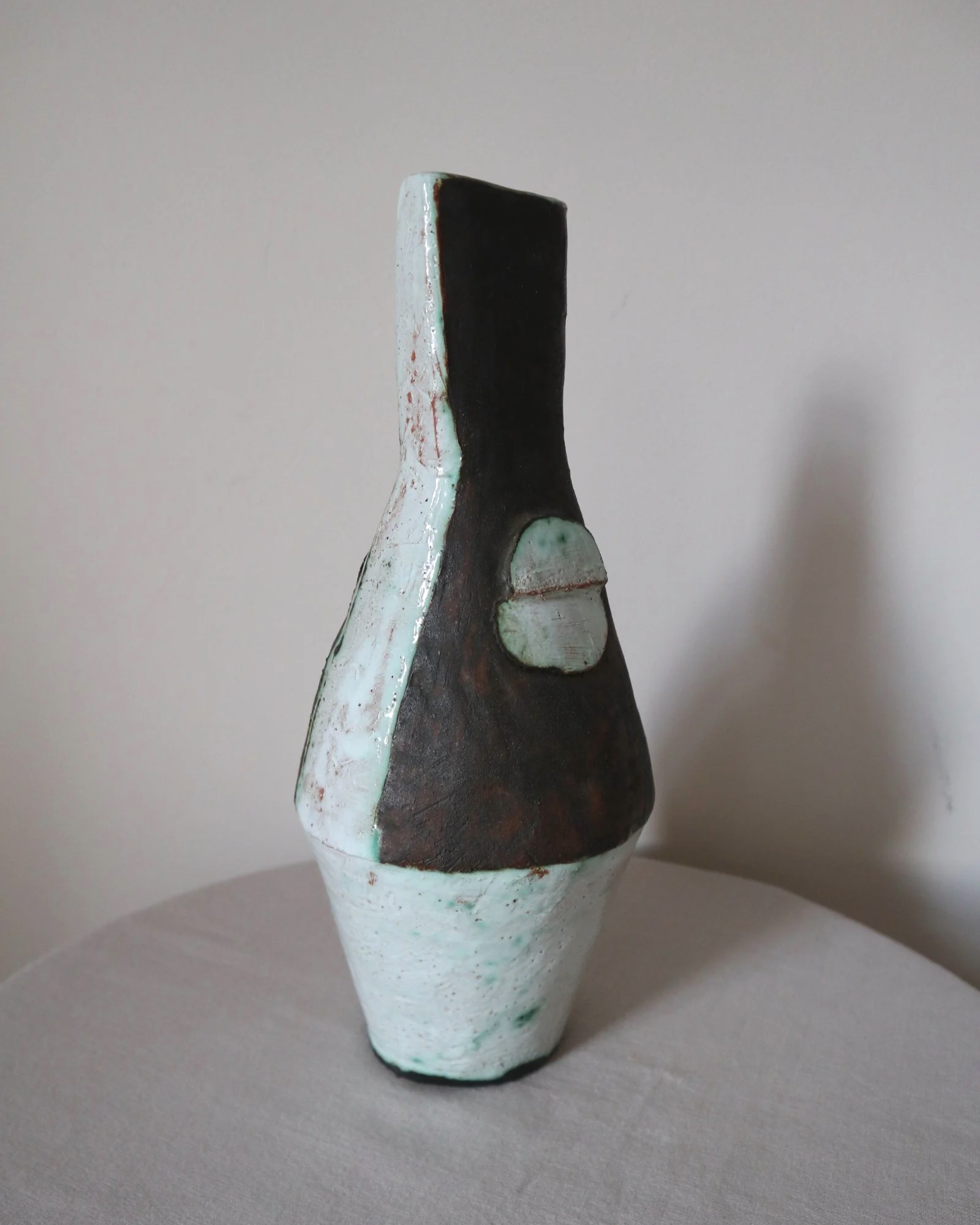 Vintage hand-built ceramic Brutalist art vase, featuring an abstract, asymmetrical design with textured white, dark brown, and subtle green glazes.