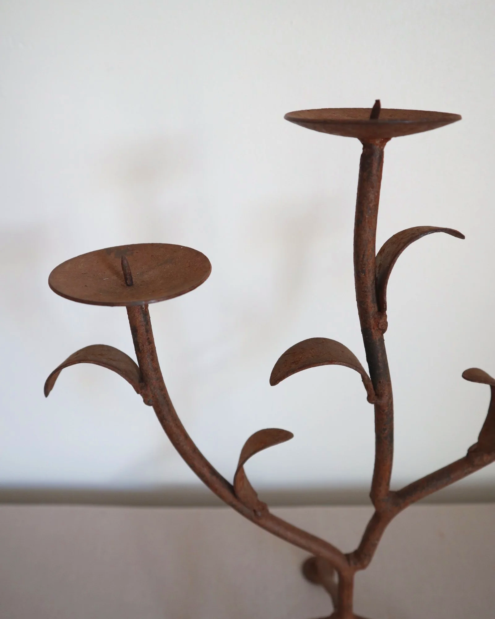 Pair of mid-century, sculptural hand crafted wrought iron 3-arm candle holders with decorative leaves and four footed base.