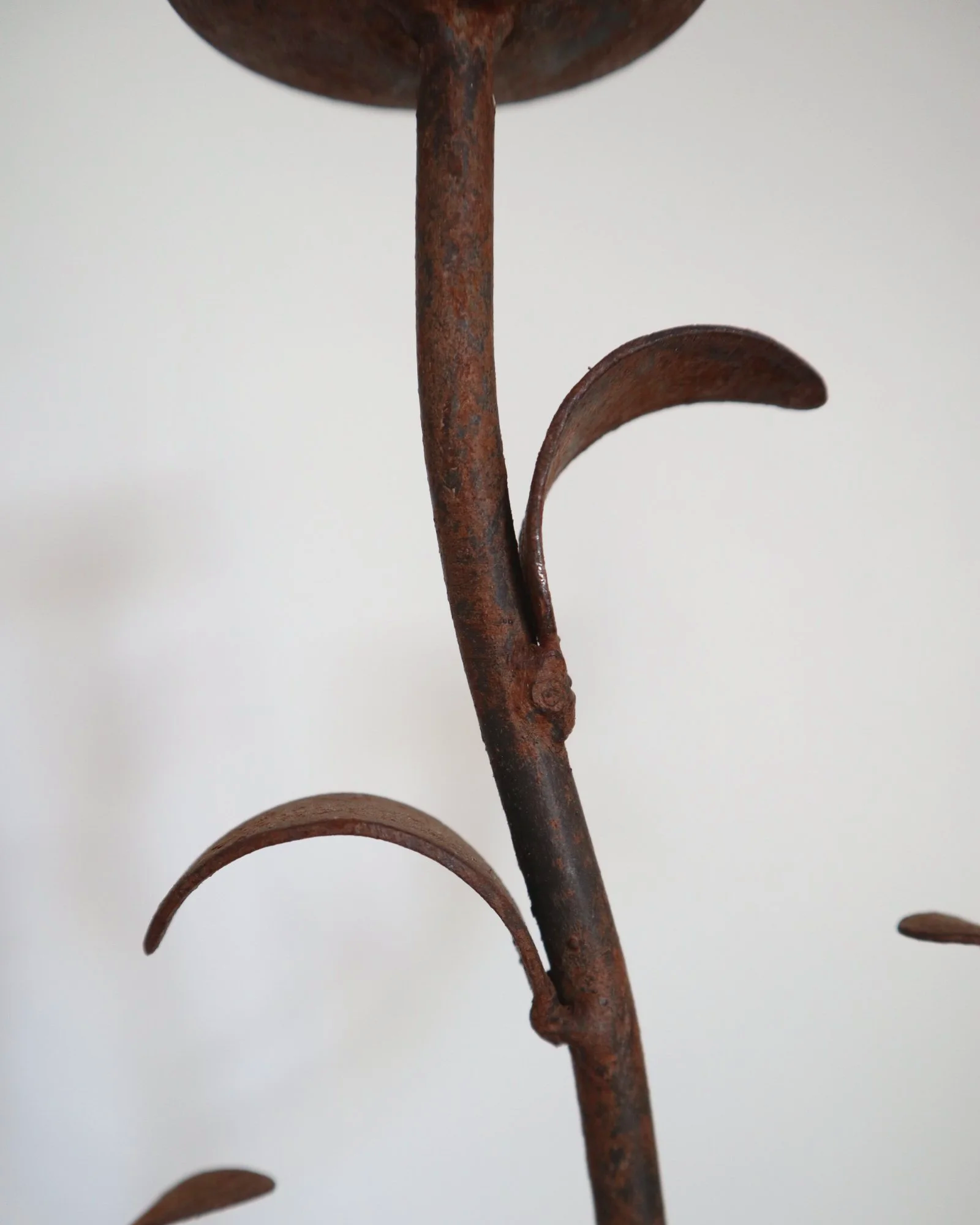 Pair of mid-century, sculptural hand crafted wrought iron 3-arm candle holders with decorative leaves and four footed base.