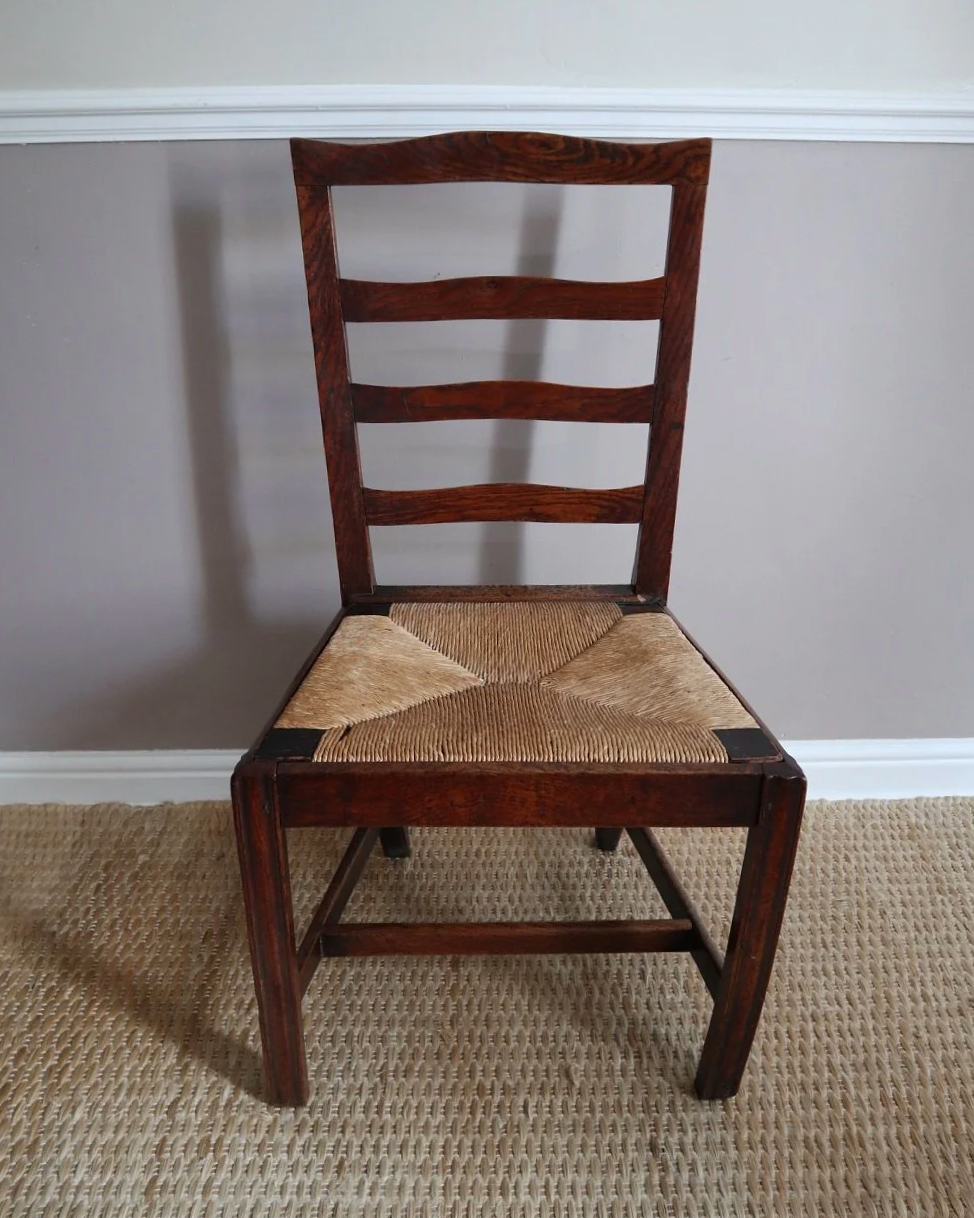 Pair of sculptural rustic oak ladder back dining chairs with rush seats, circa 1930s.