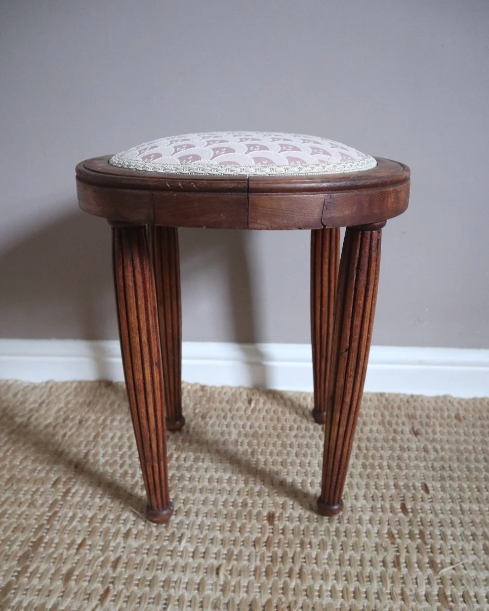 Antique Regency style carved wooden stool with four reeded tapered legs and dusky pink patterned upholstered seat.