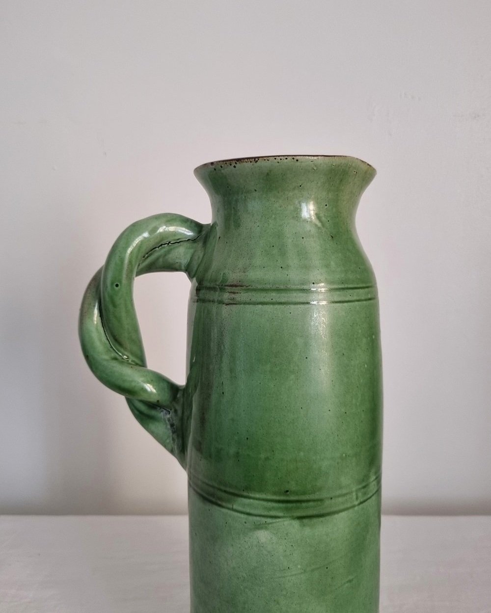 Tall studio pottery leaf green glazed water pitcher jug with twisted handle and banded centre. Marked Schofield Penrith.