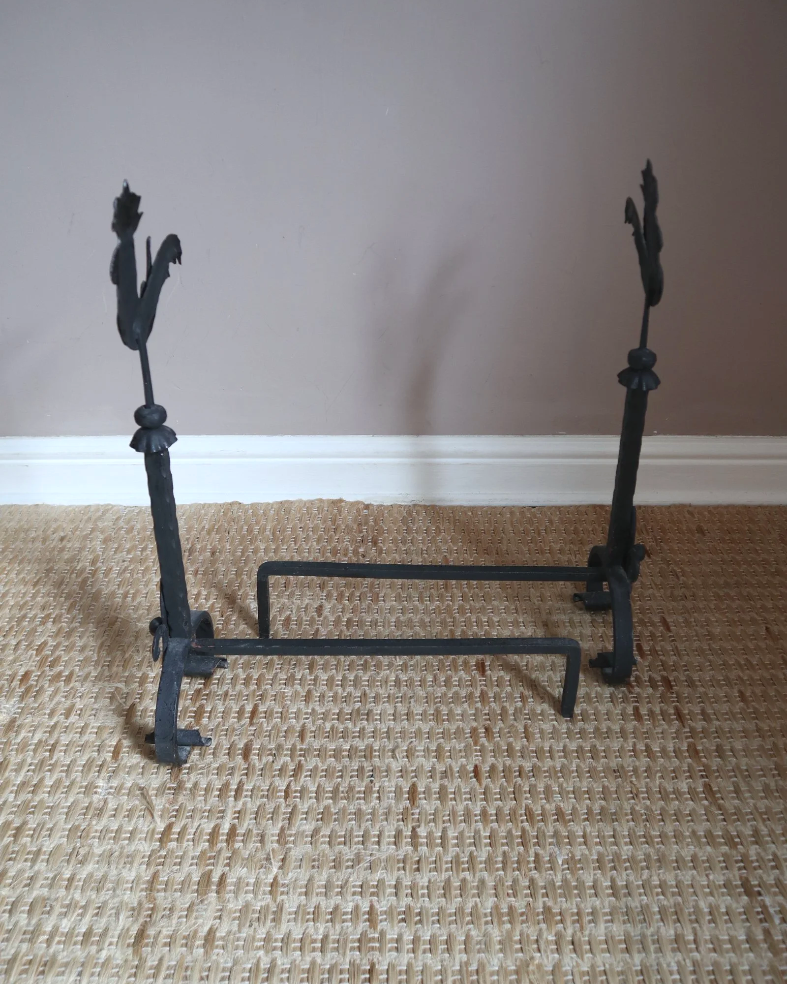 Pair of black wrought-iron andirons or firedogs featuring stylized rooster finials, circa mid-20th century.