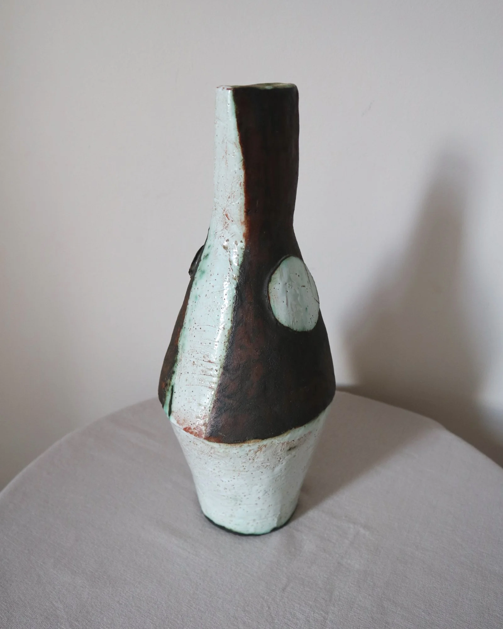 Vintage hand-built ceramic Brutalist art vase, featuring an abstract, asymmetrical design with textured white, dark brown, and subtle green glazes.