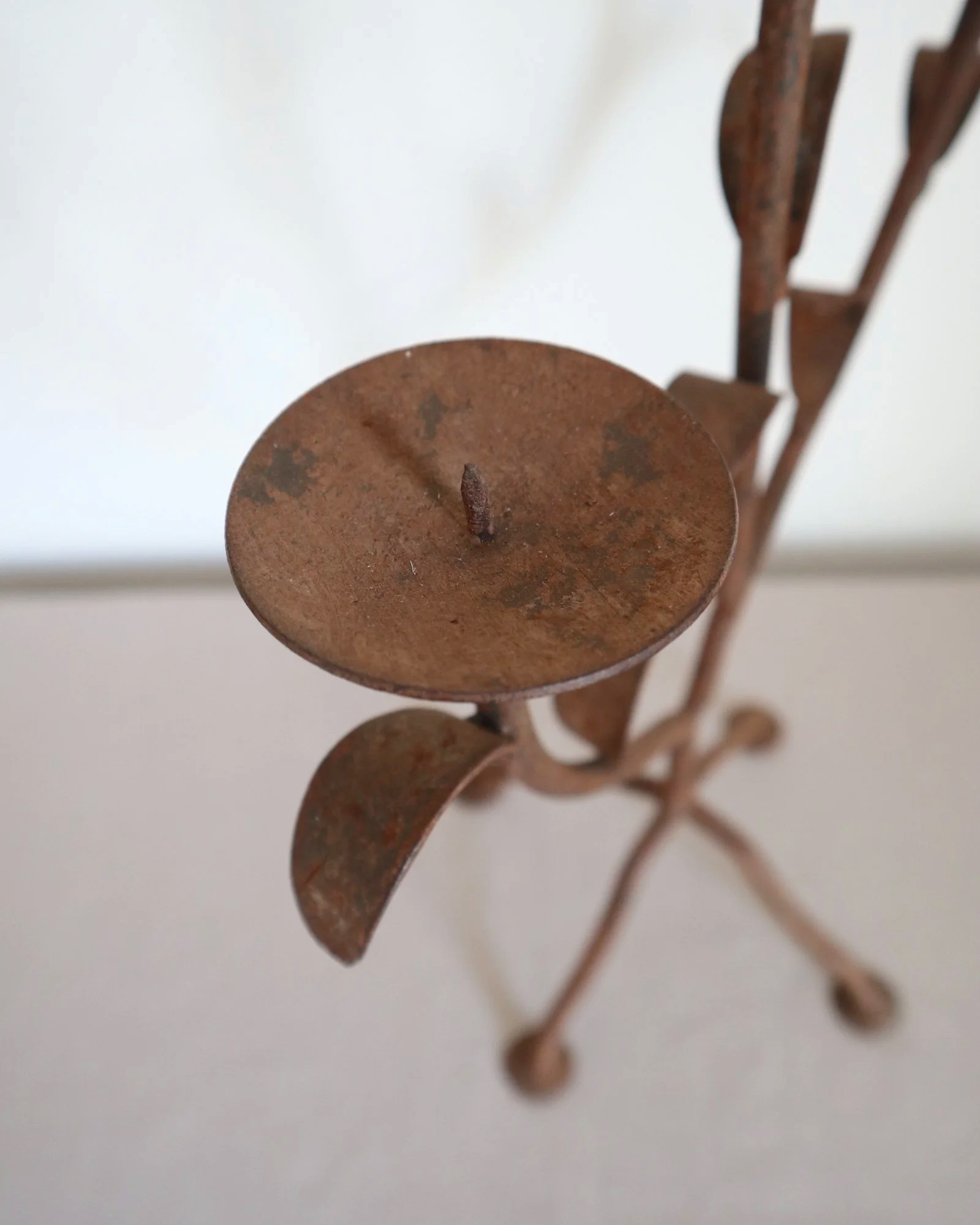Pair of mid-century, sculptural hand crafted wrought iron 3-arm candle holders with decorative leaves and four footed base.