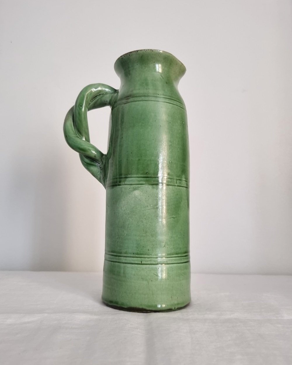 Tall studio pottery leaf green glazed water pitcher jug with twisted handle and banded centre. Marked Schofield Penrith.