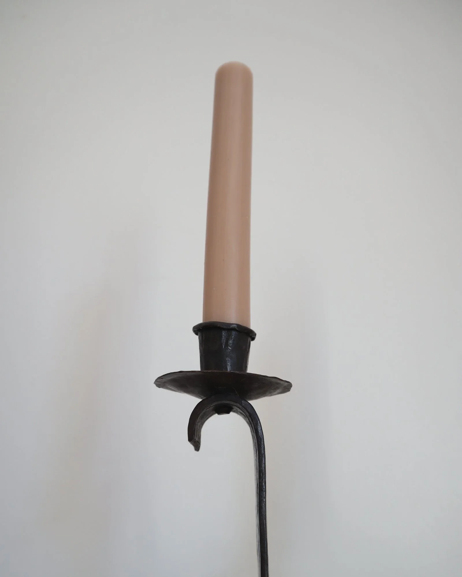 Heavy Brutalist style forged iron candleholder with off set double arms and circular base.