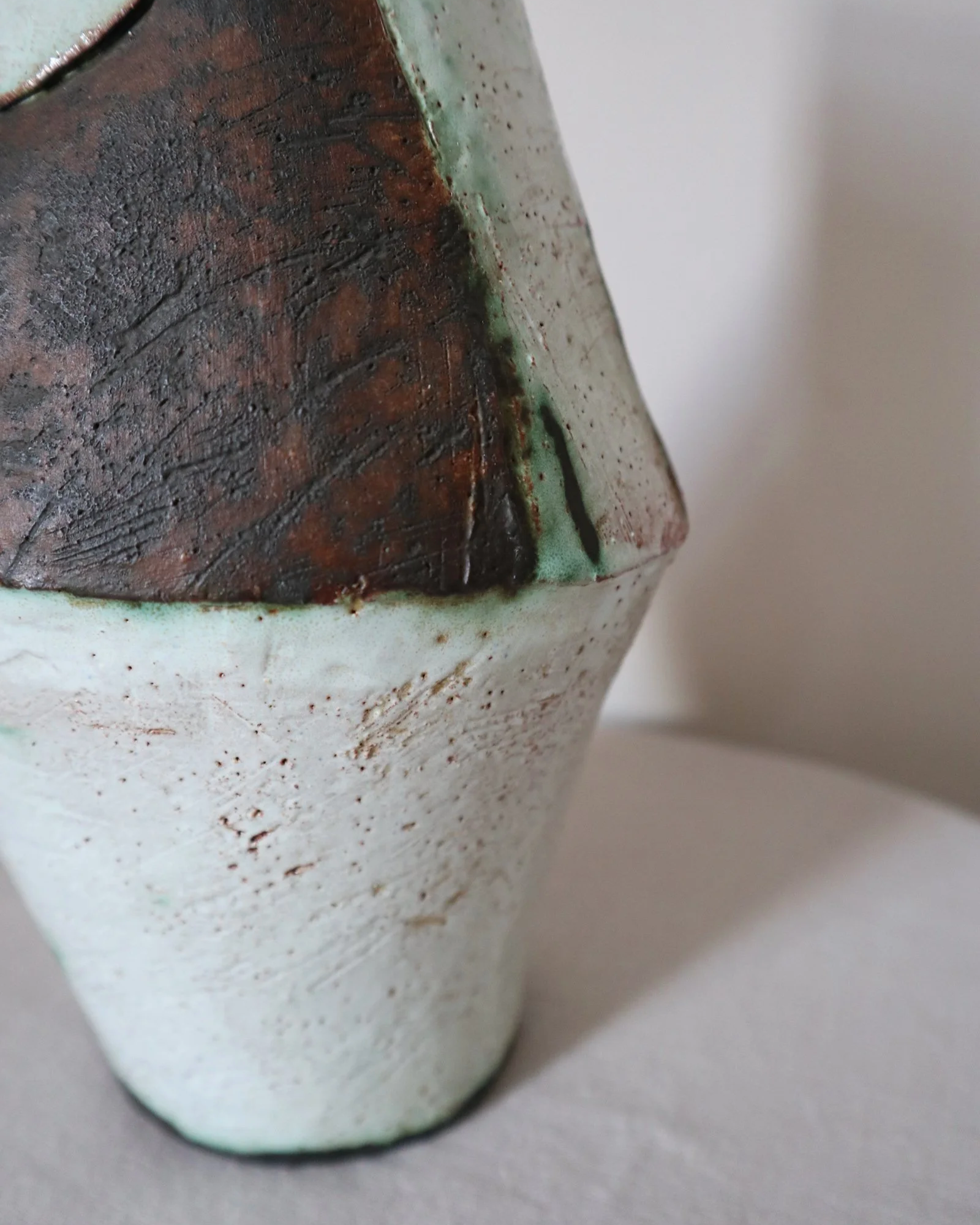 Vintage hand-built ceramic Brutalist art vase, featuring an abstract, asymmetrical design with textured white, dark brown, and subtle green glazes.