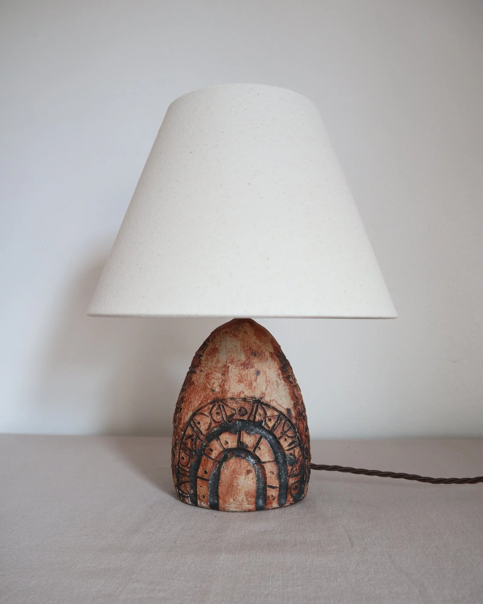Small Brutalist stoneware table lamp by British potter Bernard Rooke. With stamped, rune-like impressions. Circa 1970s.