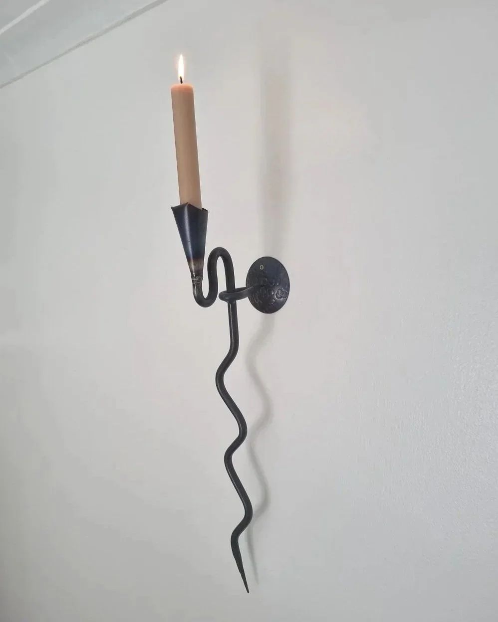 Large Swedish black iron wall sconce candleholder with wavy design. Circa 1960s.