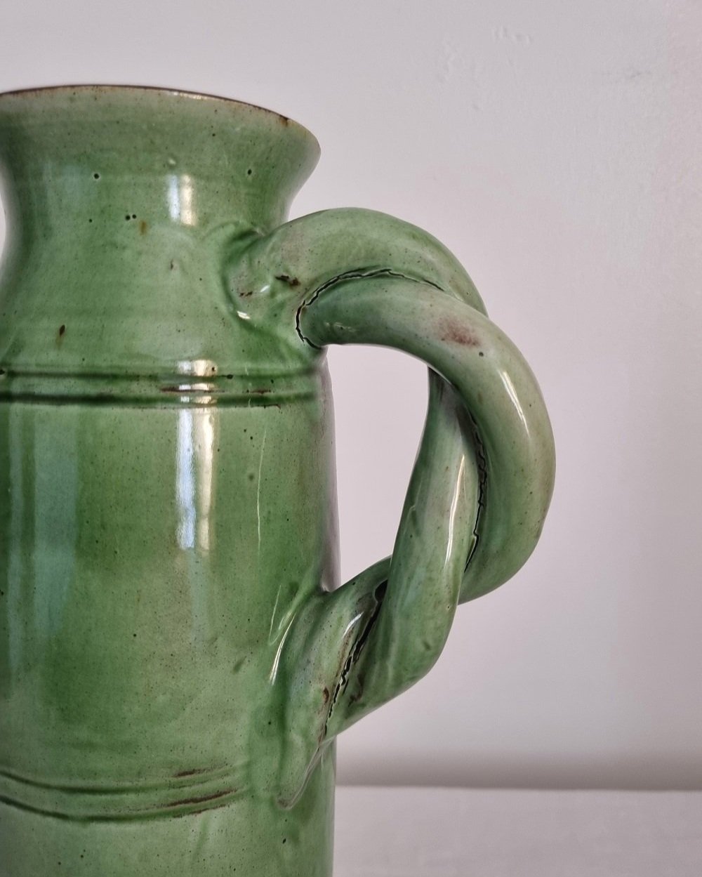Tall studio pottery leaf green glazed water pitcher jug with twisted handle and banded centre. Marked Schofield Penrith.