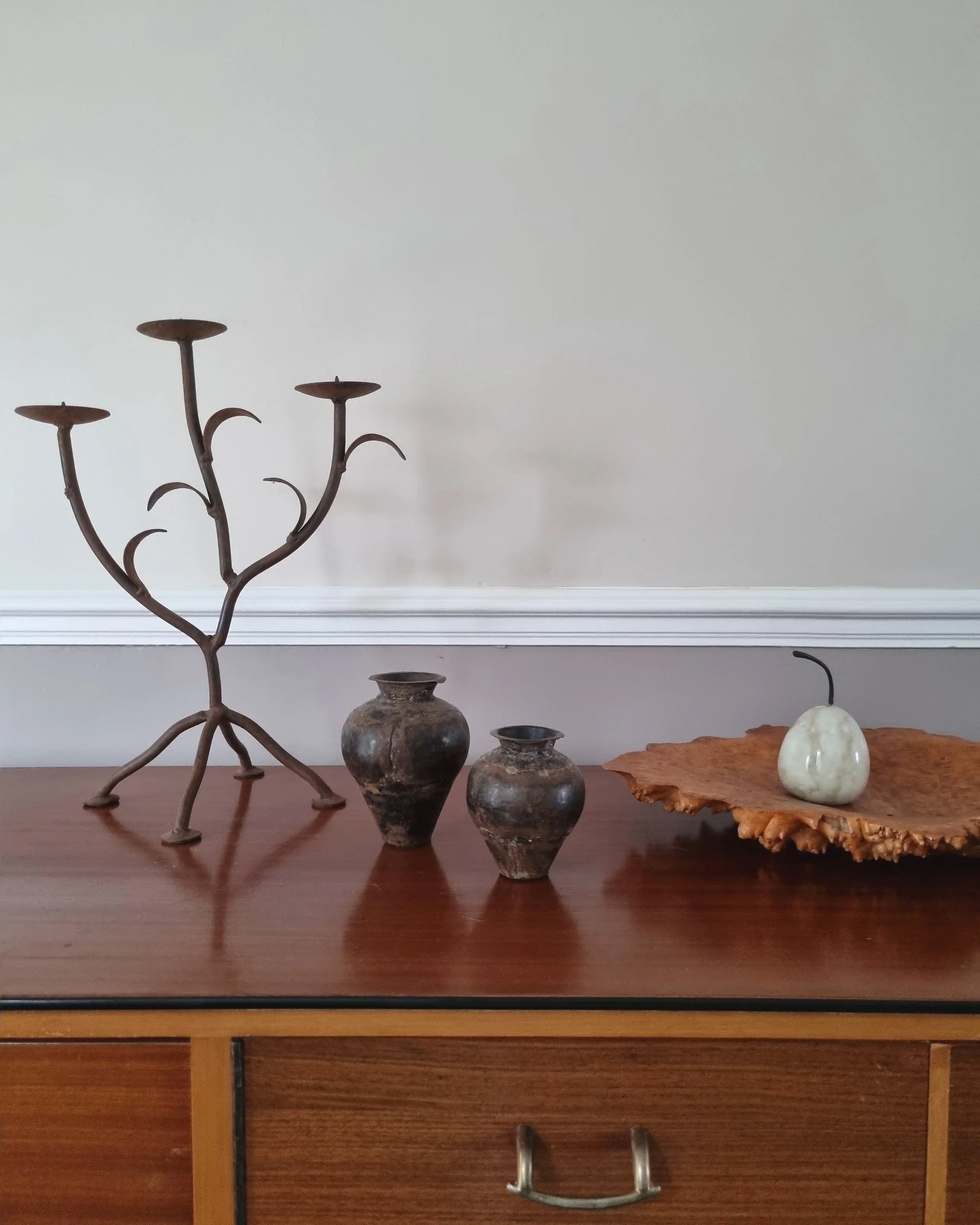 Pair of mid-century, sculptural hand crafted wrought iron 3-arm candle holders with decorative leaves and four footed base.