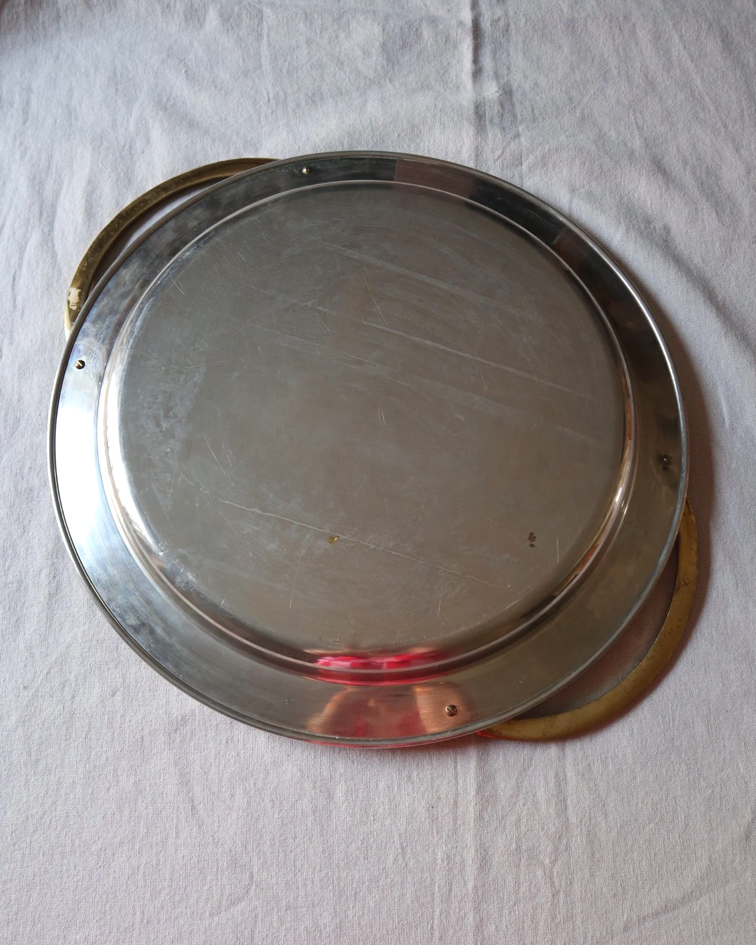 Large mid century circular shiny metal serving tray with elegant brass rope design handles.