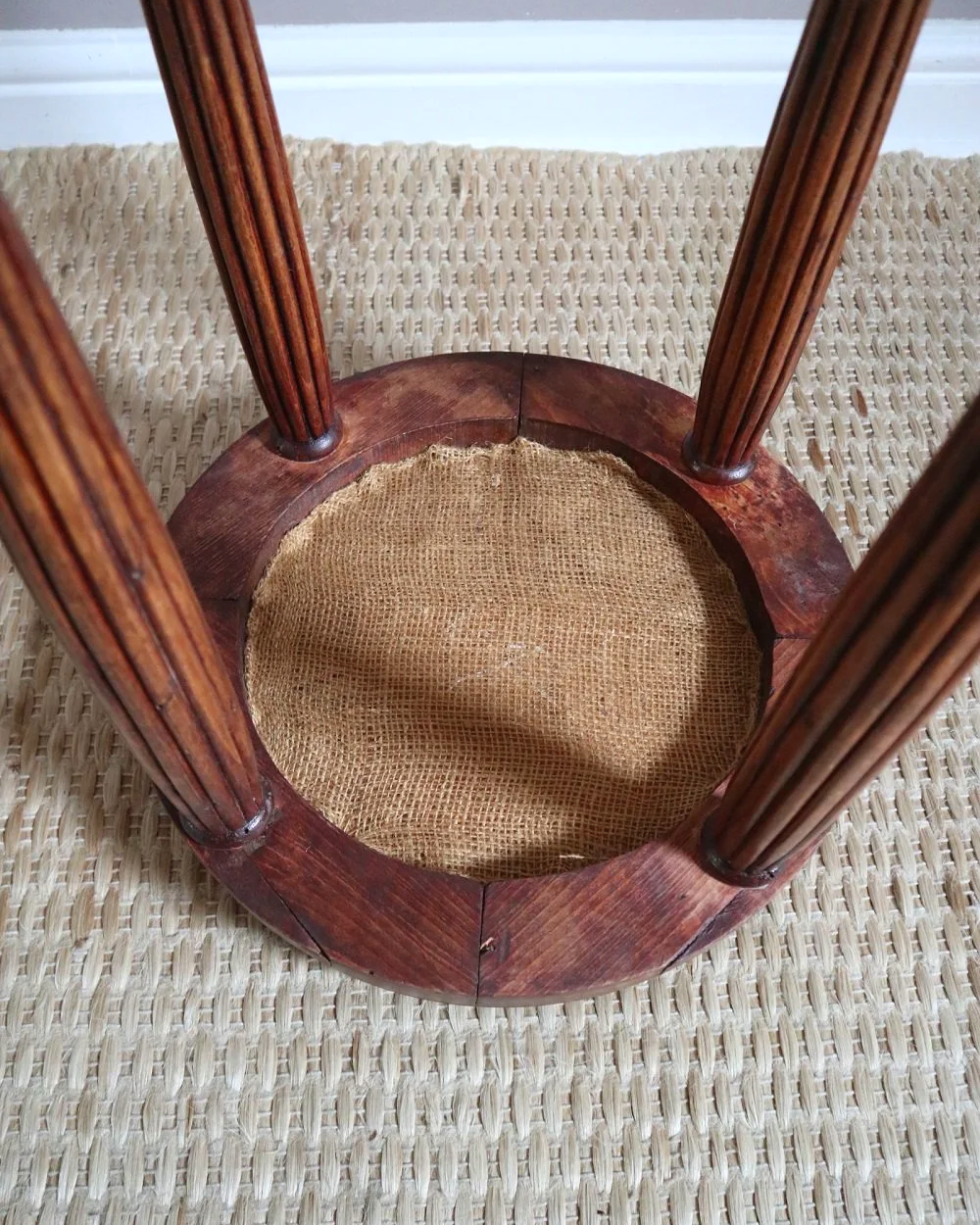 Antique Regency style carved wooden stool with four reeded tapered legs and dusky pink patterned upholstered seat.