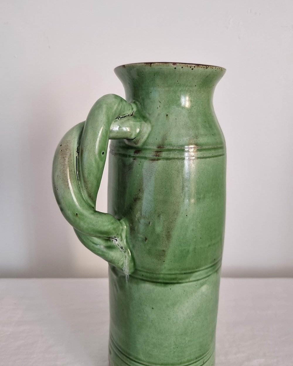 Tall studio pottery leaf green glazed water pitcher jug with twisted handle and banded centre. Marked Schofield Penrith.