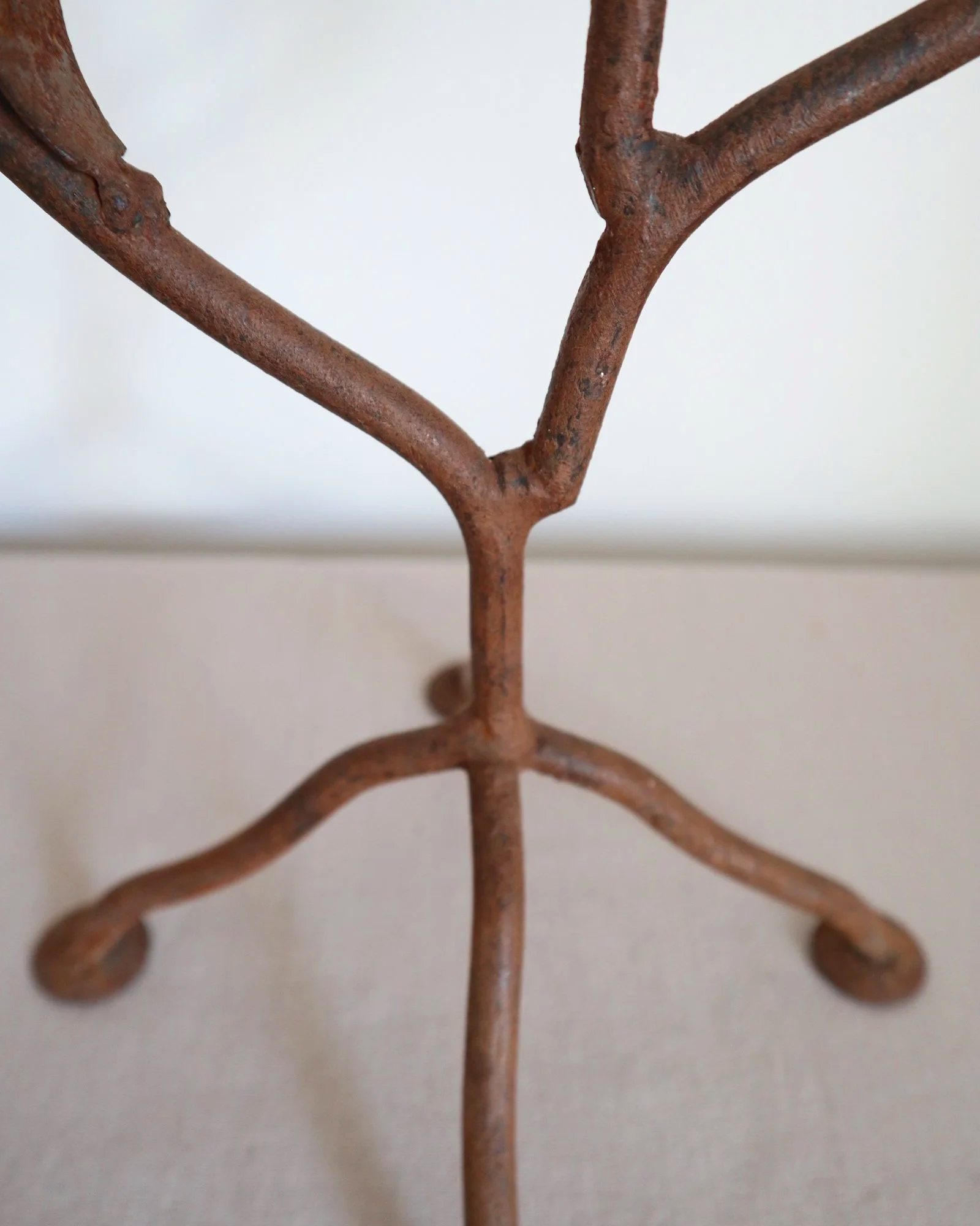 Pair of mid-century, sculptural hand crafted wrought iron 3-arm candle holders with decorative leaves and four footed base.