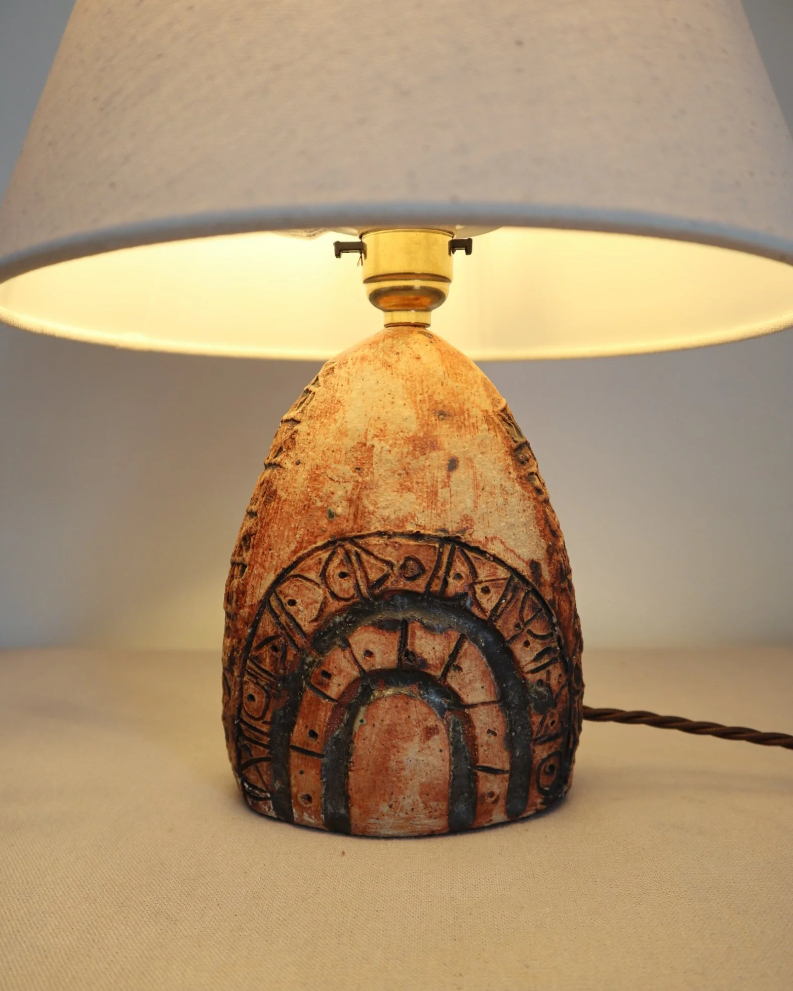 Small Brutalist stoneware table lamp by British potter Bernard Rooke. With stamped, rune-like impressions. Circa 1970s.