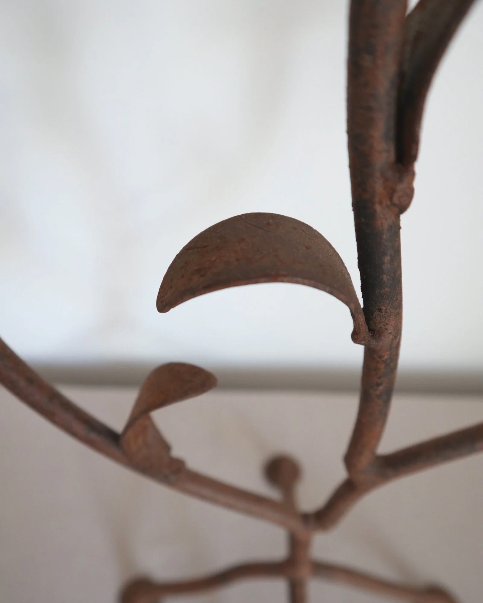 Pair of mid-century, sculptural hand crafted wrought iron 3-arm candle holders with decorative leaves and four footed base.