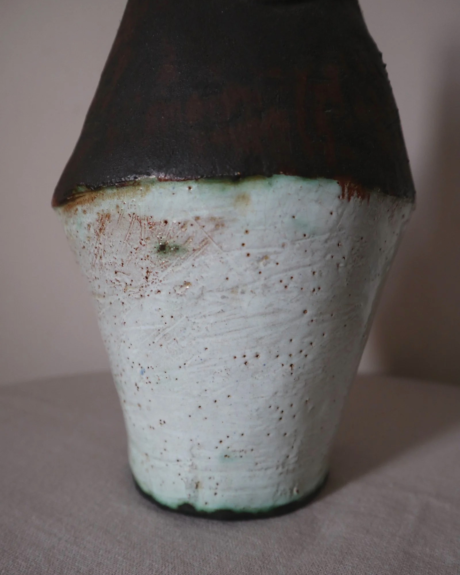Vintage hand-built ceramic Brutalist art vase, featuring an abstract, asymmetrical design with textured white, dark brown, and subtle green glazes.