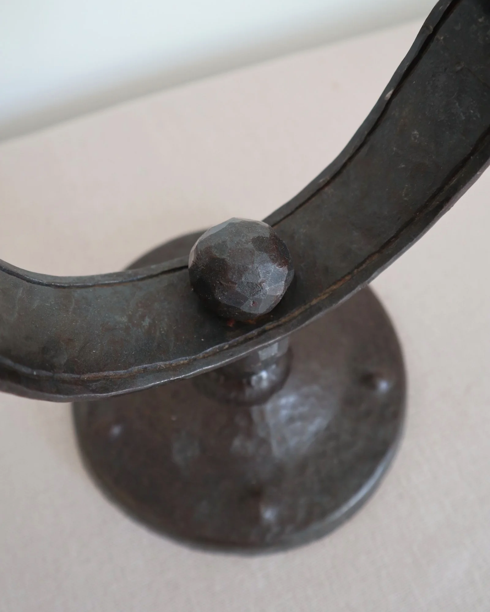 Heavy Brutalist style forged iron candleholder with off set double arms and circular base.