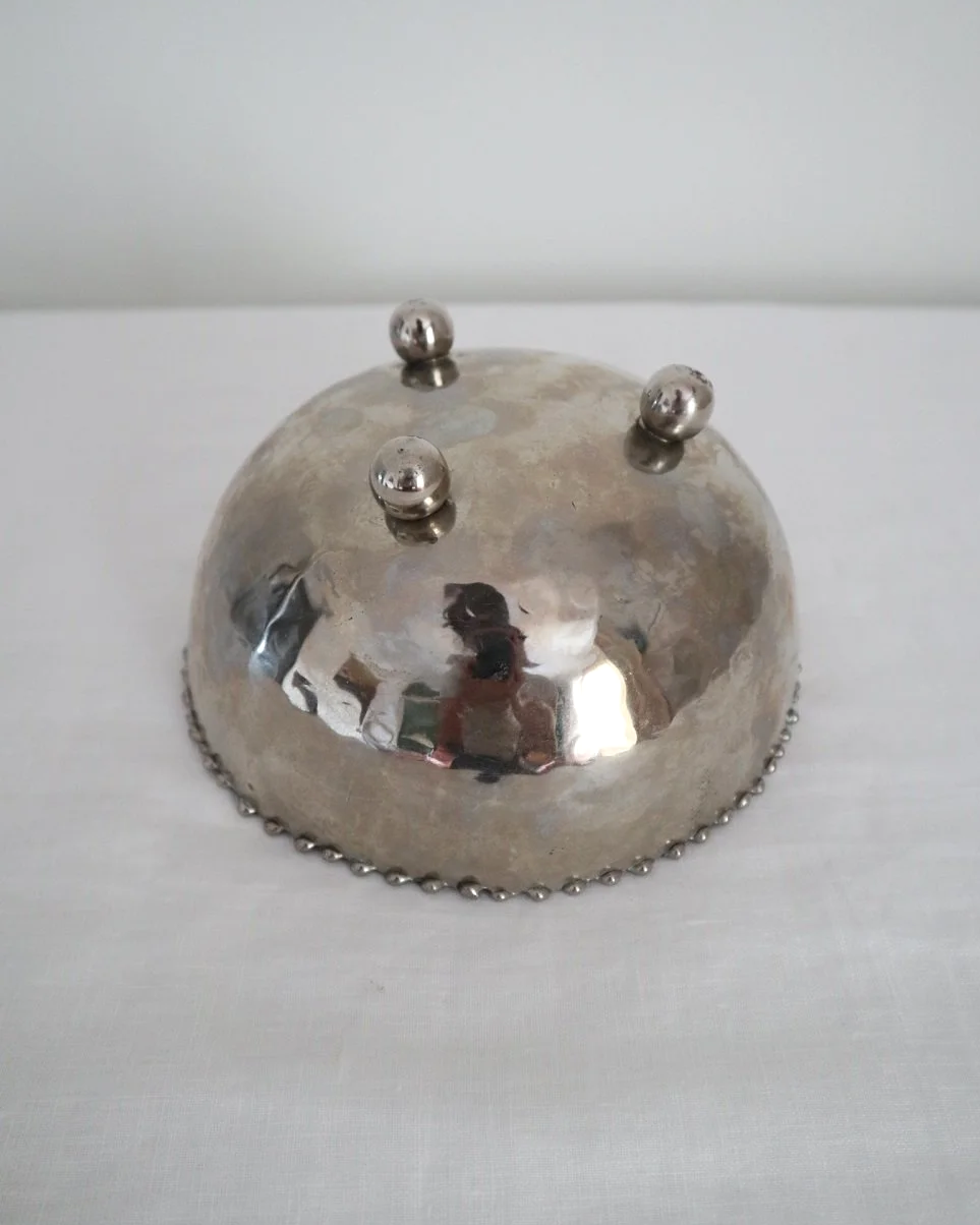 Small hammered metal lightweight circular dish with three ball feet and decorative beaded edging.