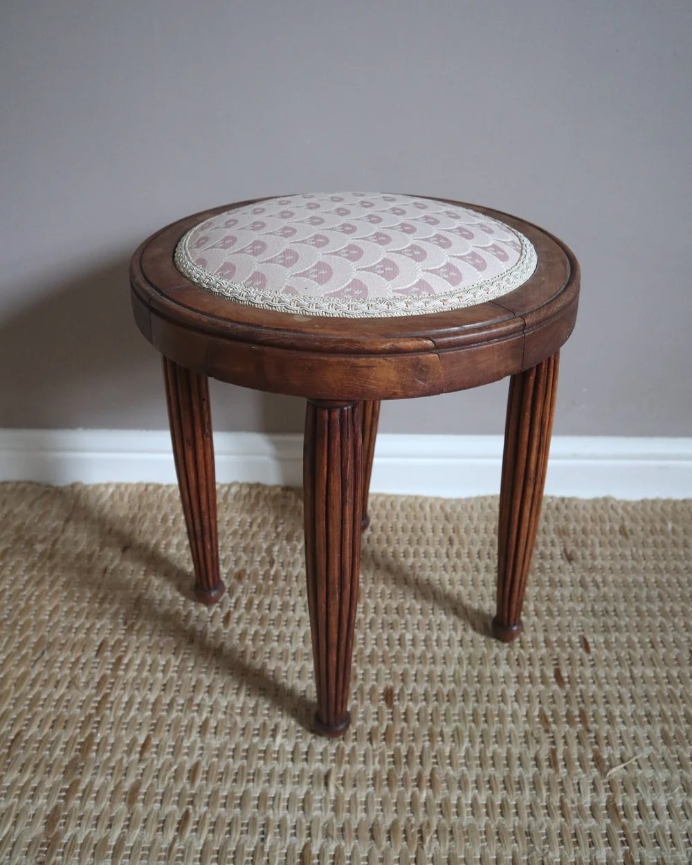 Antique Regency style carved wooden stool with four reeded tapered legs and dusky pink patterned upholstered seat.
