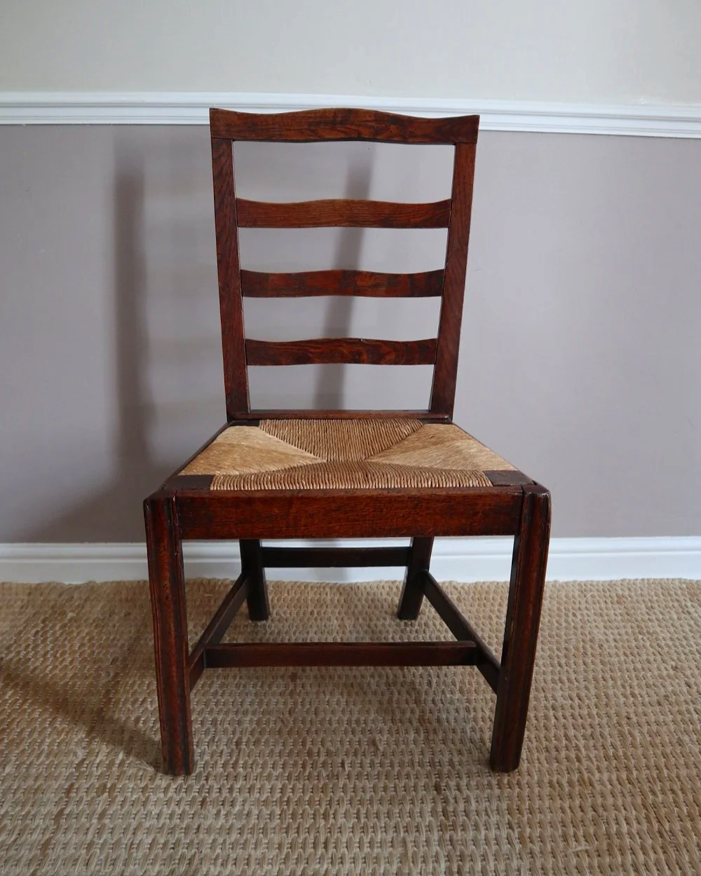 Pair of sculptural rustic oak ladder back dining chairs with rush seats, circa 1930s.