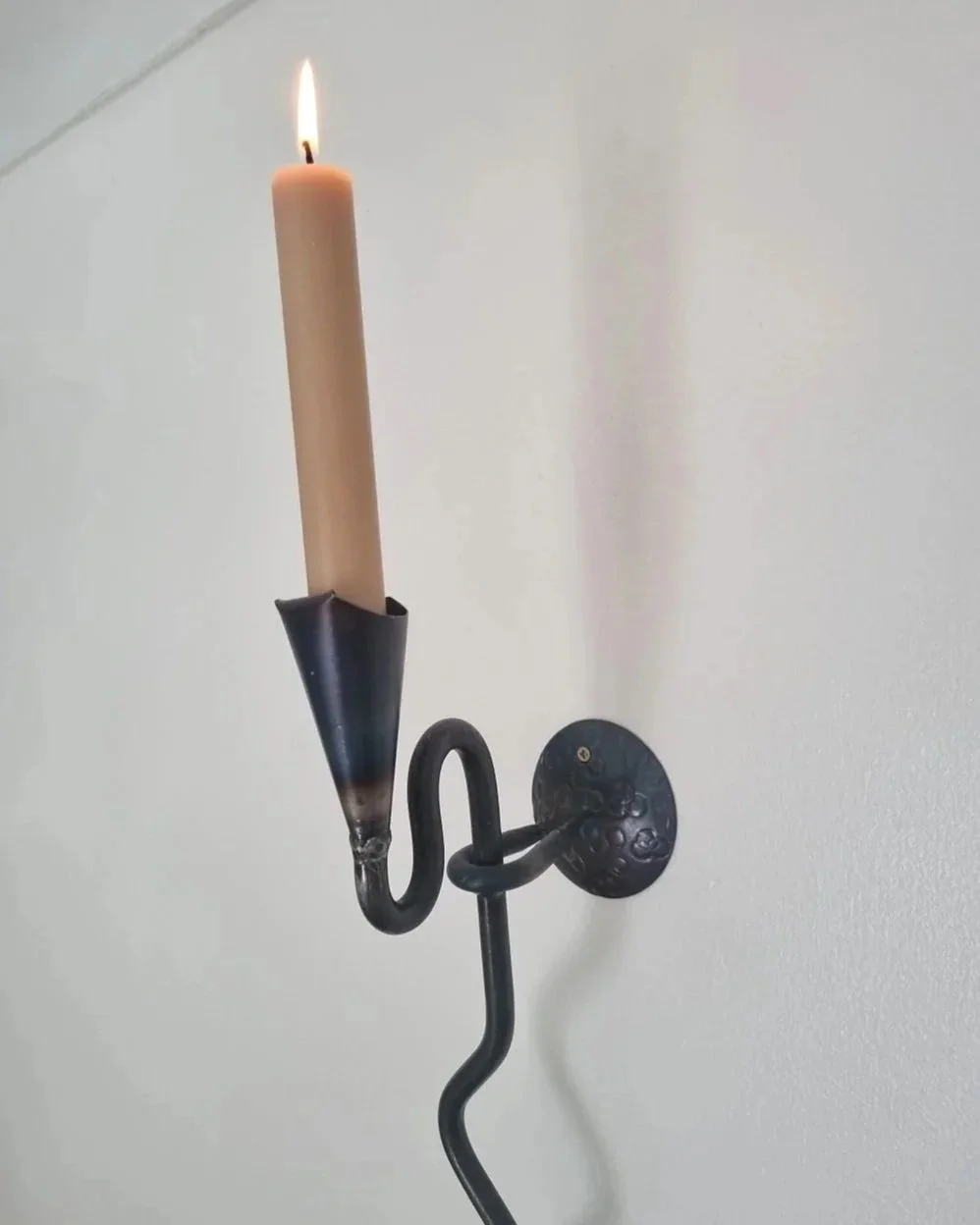 Large Swedish black iron wall sconce candleholder with wavy design. Circa 1960s.