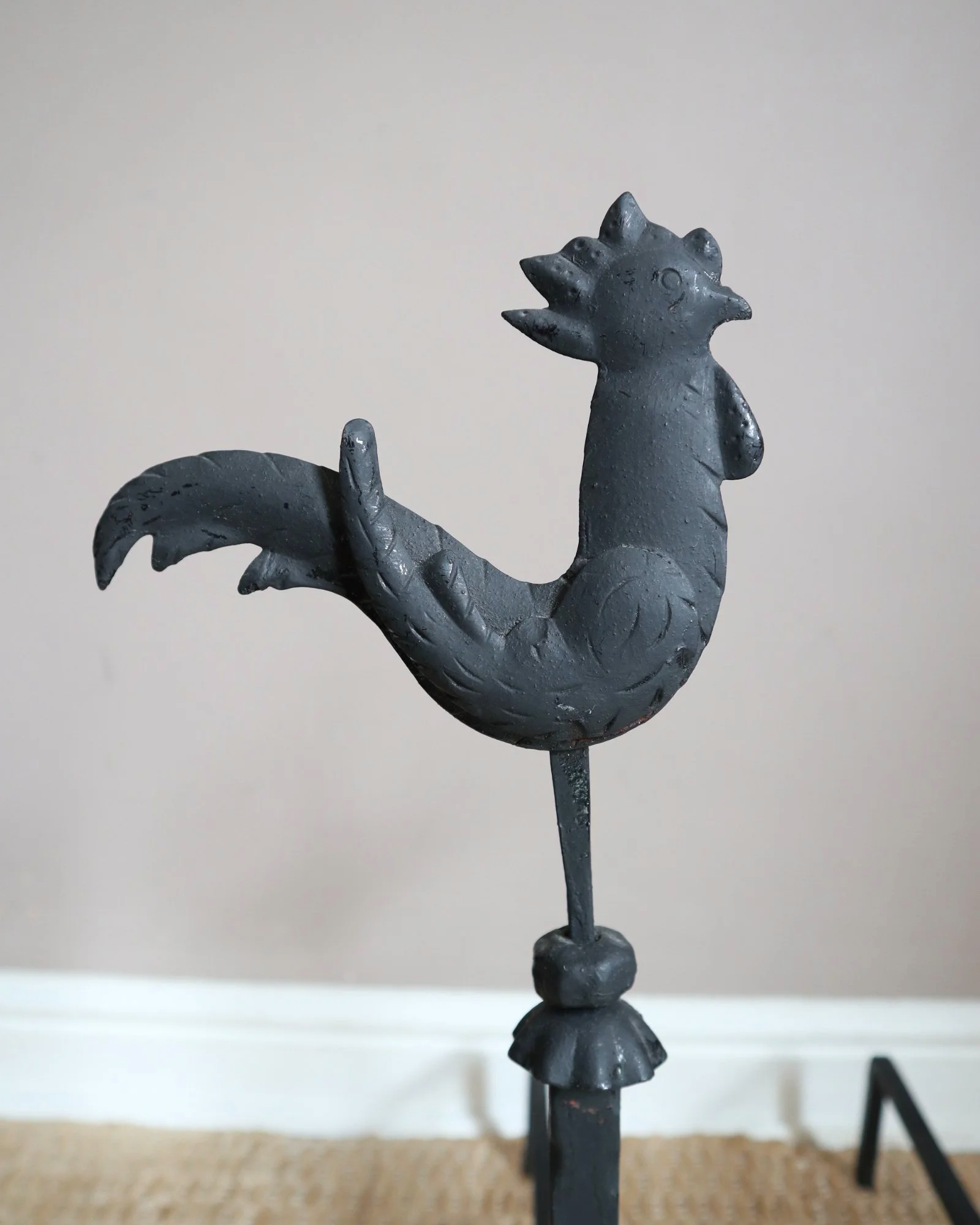 Pair of black wrought-iron andirons or firedogs featuring stylized rooster finials, circa mid-20th century.