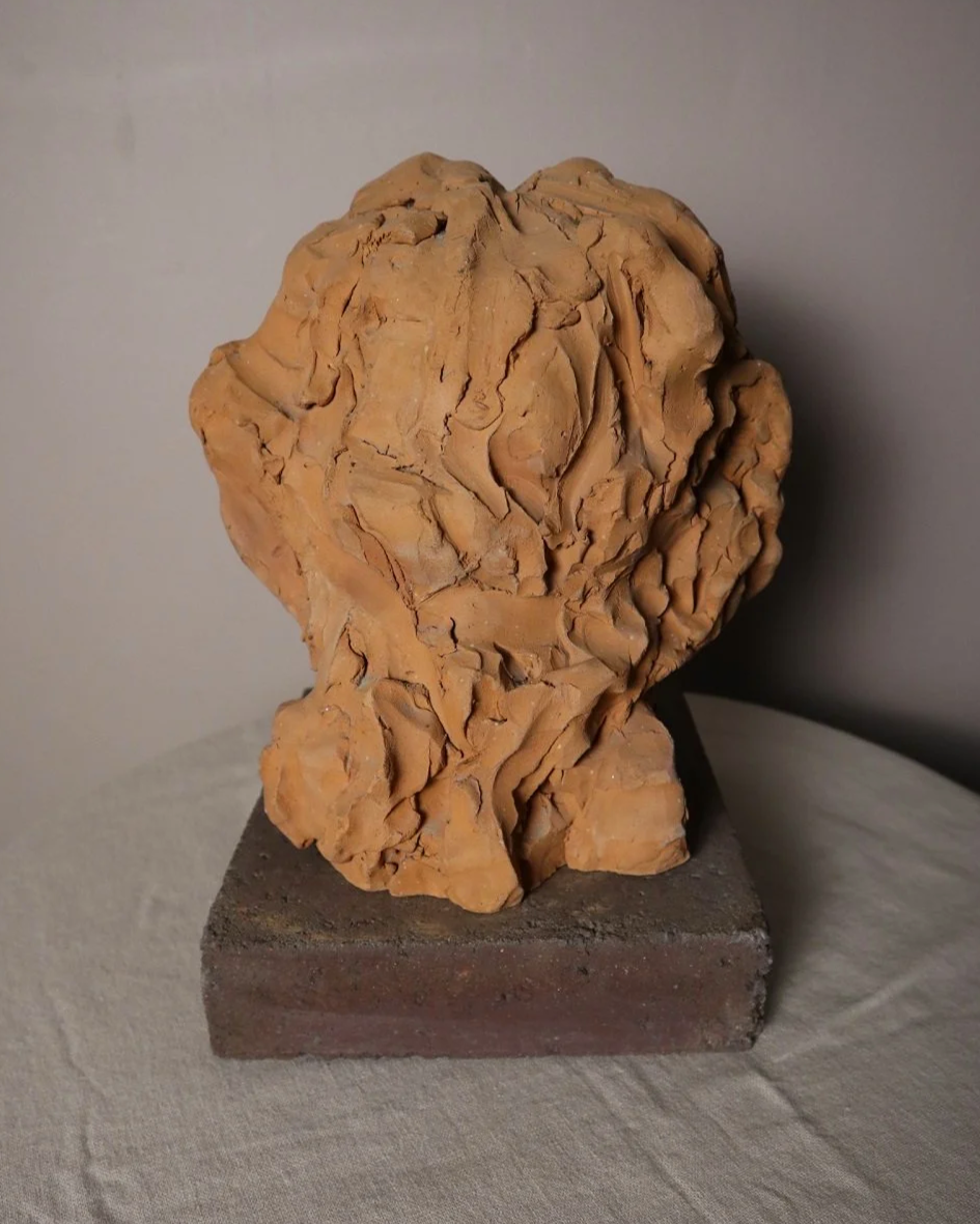 A signed, 20th century art studio terracotta female bust with stone display plinth.