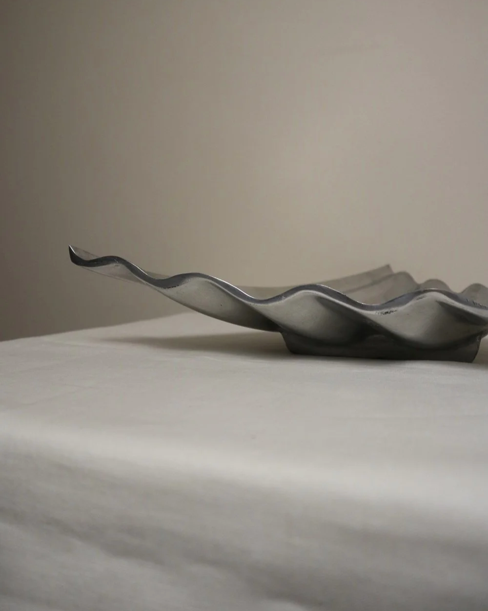 Large mid century, shiny cast aluminium triangular display dish with wavy edge.