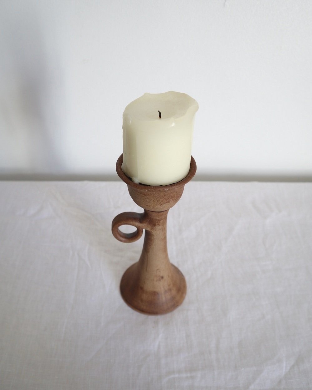 Rustic handmade studio pottery sculptural candleholder with curled circular handle.