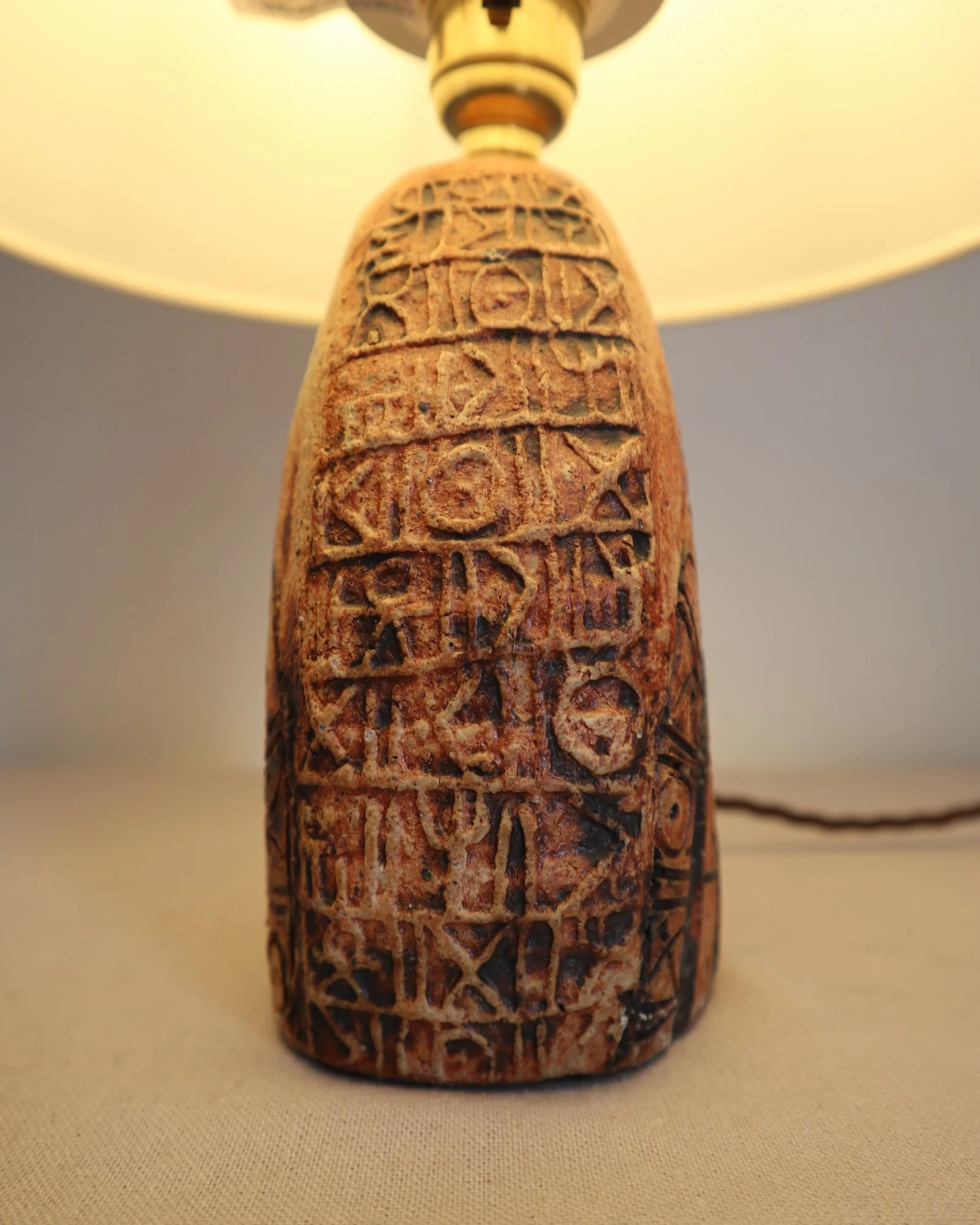 Small Brutalist stoneware table lamp by British potter Bernard Rooke. With stamped, rune-like impressions. Circa 1970s.