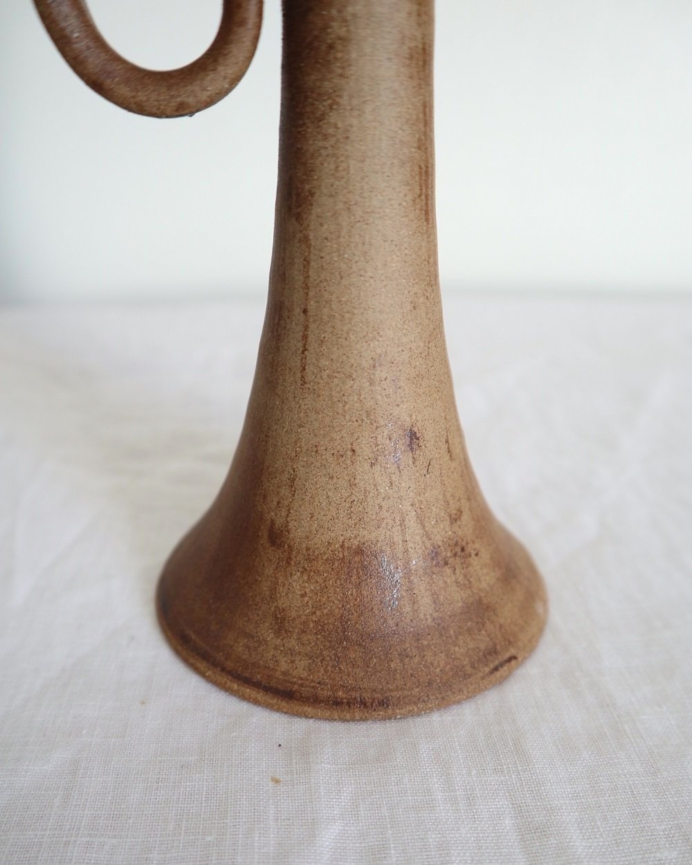 Rustic handmade studio pottery sculptural candleholder with curled circular handle.
