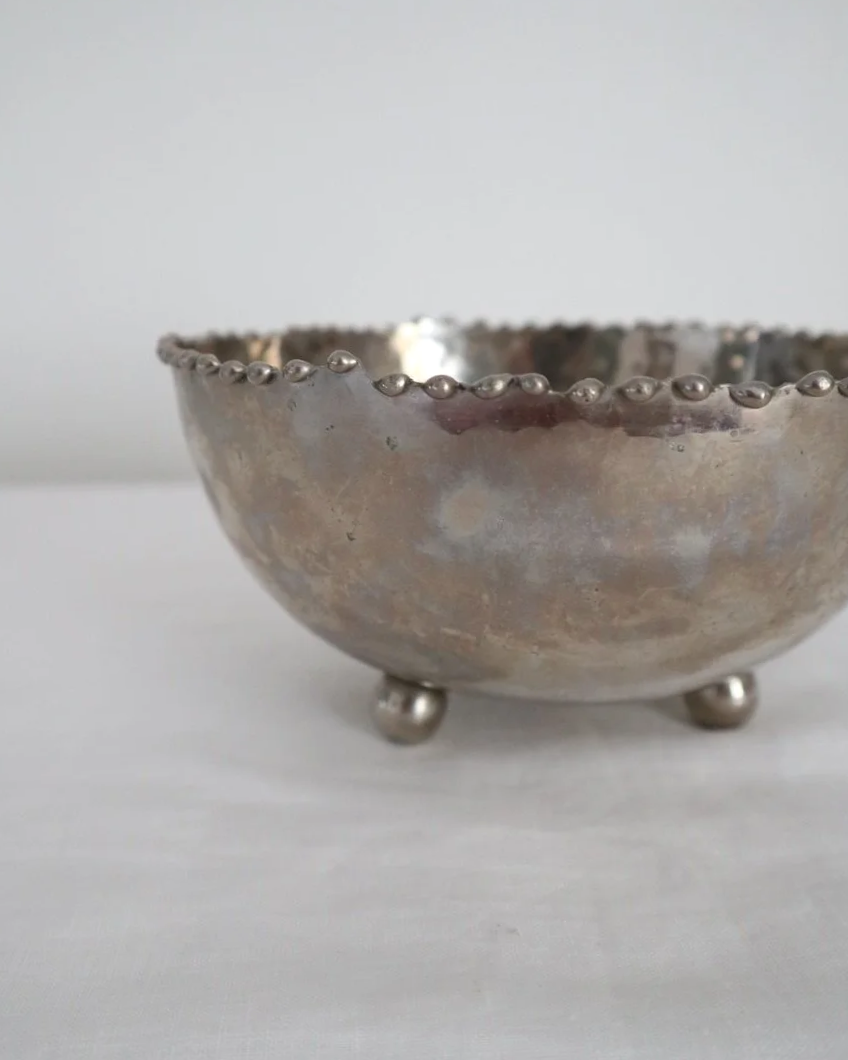 Small hammered metal lightweight circular dish with three ball feet and decorative beaded edging.