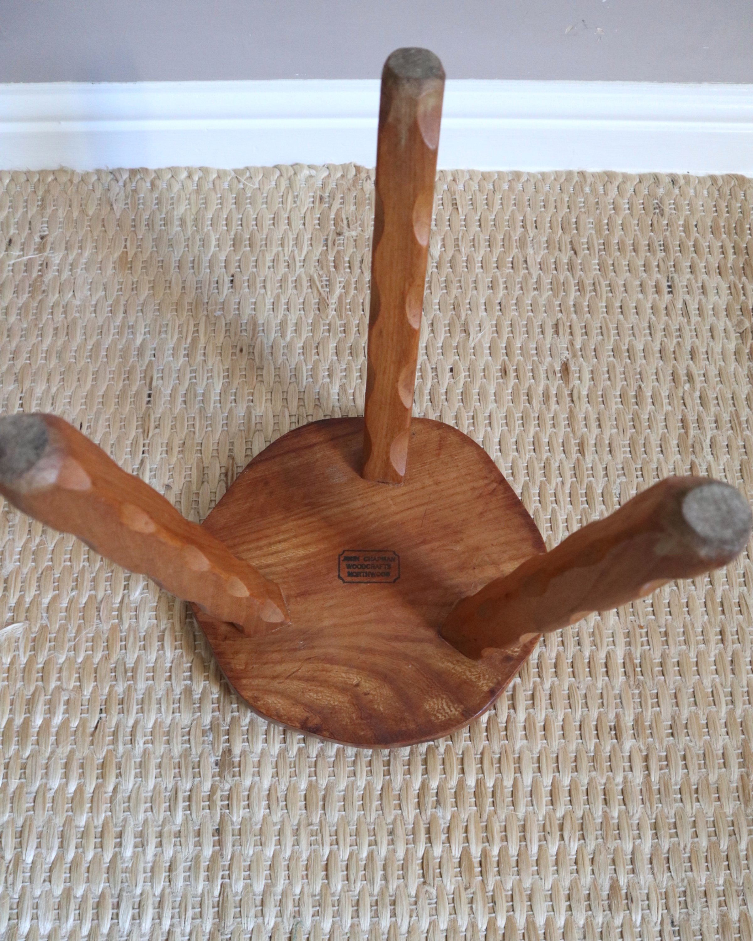 Vintage rustic handmade warm wooden tripod stool with carved legs. Stamped 'John Chapman Woodcrafts Northwood'.