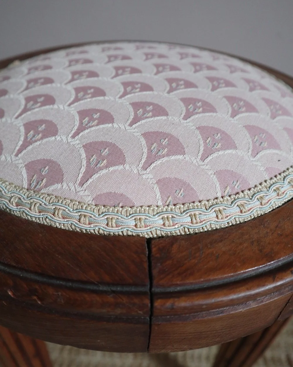Antique Regency style carved wooden stool with four reeded tapered legs and dusky pink patterned upholstered seat.
