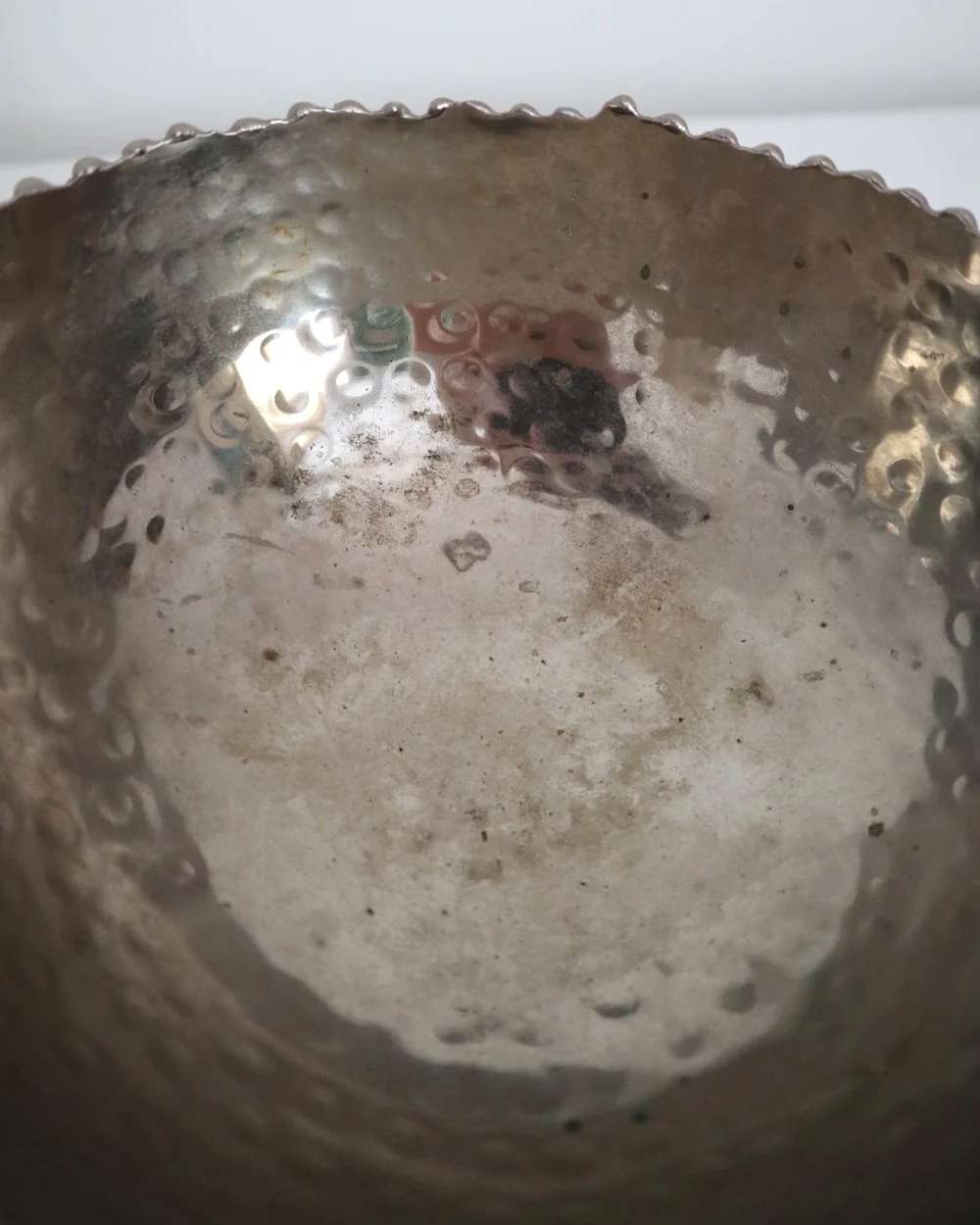 Small hammered metal lightweight circular dish with three ball feet and decorative beaded edging.