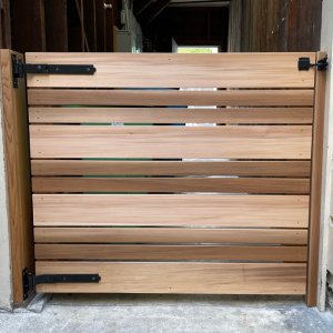 Wooden horizontal slat gate with black metal hinges